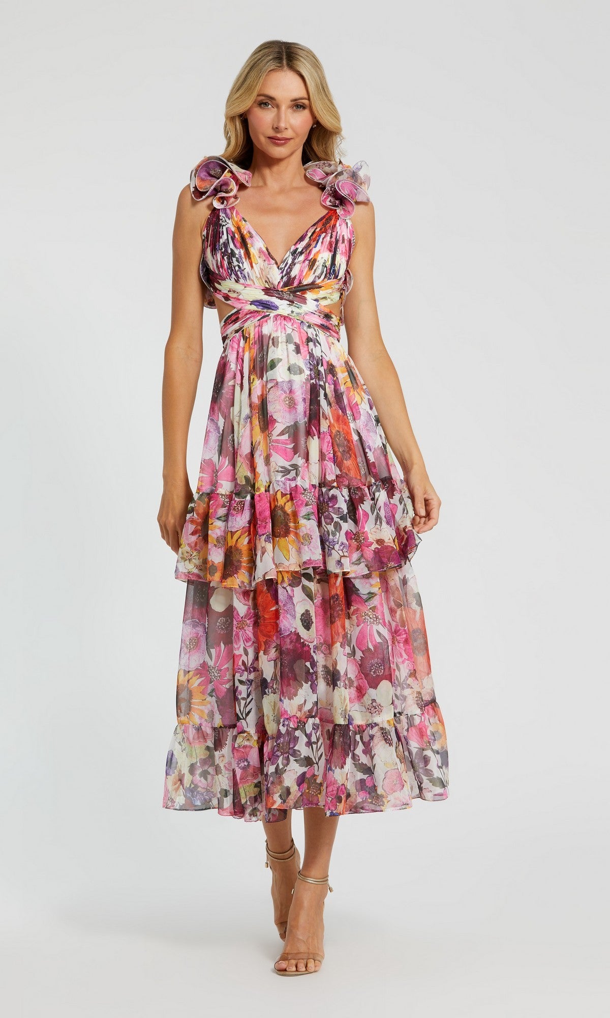 A woman models the Mac Duggal 56048 Midi Wedding Guest Dress in White Multi—a sleeveless, v-neck chiffon dress with floral print and layered ruffles—against a plain background.