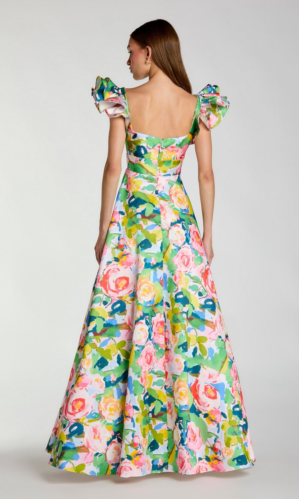 A woman facing away is wearing the Long Formal Dress: Mac Duggal 56341, a floor-length Mikado gown featuring a multicolored floral print, puffed short sleeves, and a square neckline, set against a plain background.