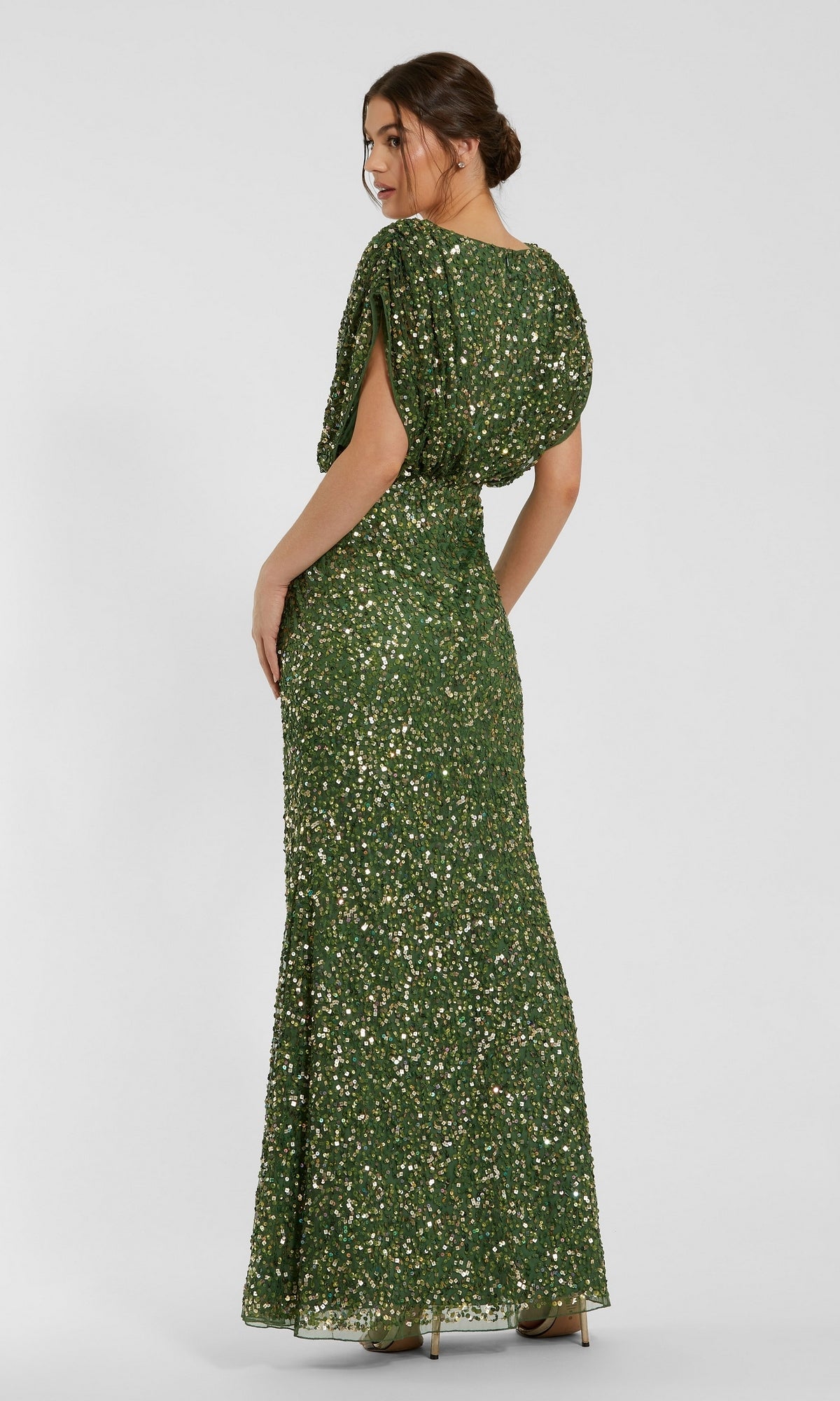 A woman in a floor-length, green “Short Sleeve Long Sequin Formal Dress: Mac Duggal 5640” stands and looks over her shoulder against a plain background.