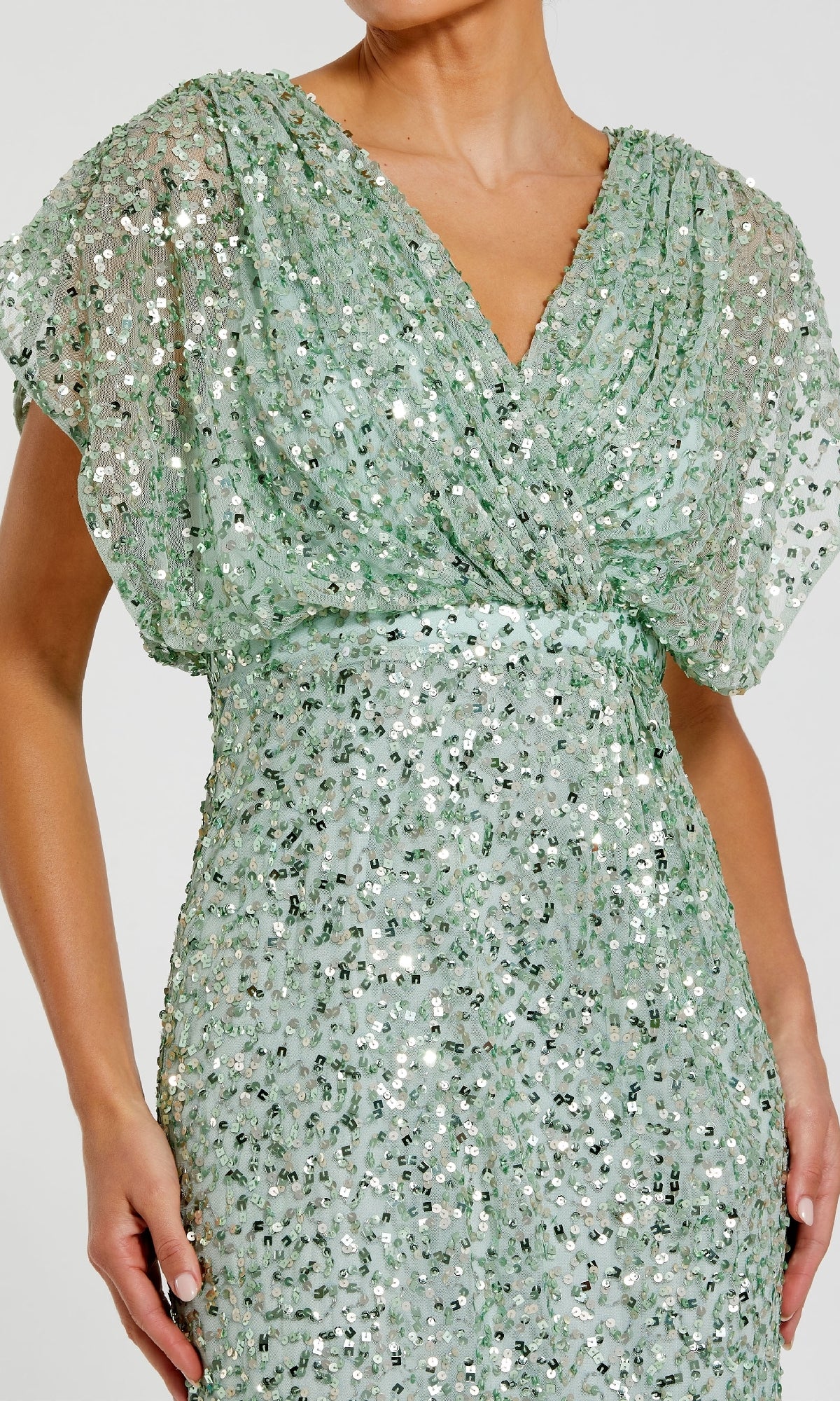 A person wearing the Mac Duggal 5640 Short Sleeve Long Sequin Formal Dress in light green, featuring a V-neck, gathered waist, and sparkling sequins.