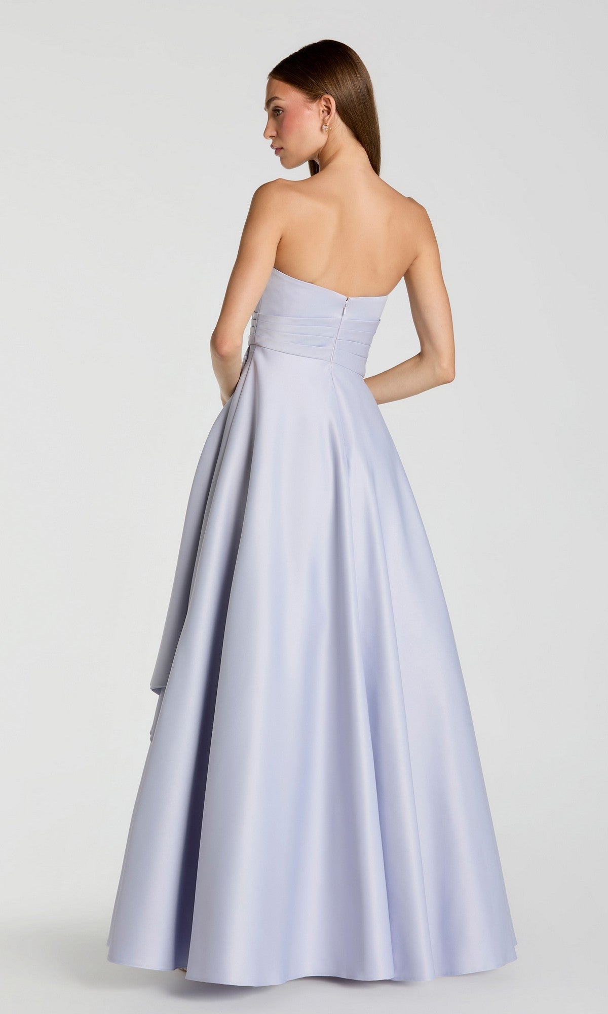 A woman stands with her hair down and arms at her sides against a plain background, modeling the Mac Duggal 56425 Long Formal Dress. The strapless, floor-length gown is crafted from pale lavender satin and showcases a minimalistic design that exudes understated elegance.