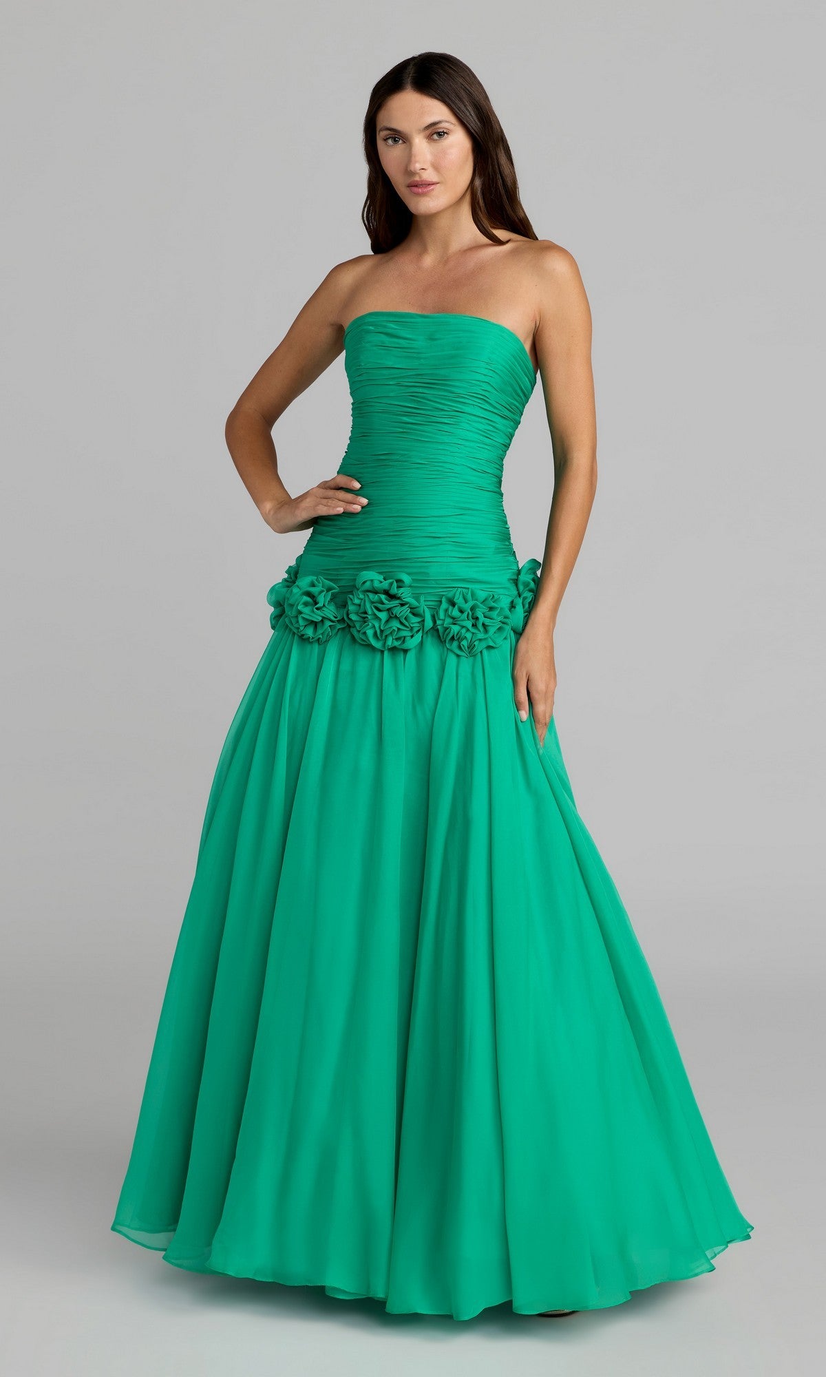 A woman stands against a plain background wearing the Mac Duggal 56428 Long Formal Dress in Spring Green—a strapless, floor-length gown featuring a ruched bodice and floral accents at the waist.