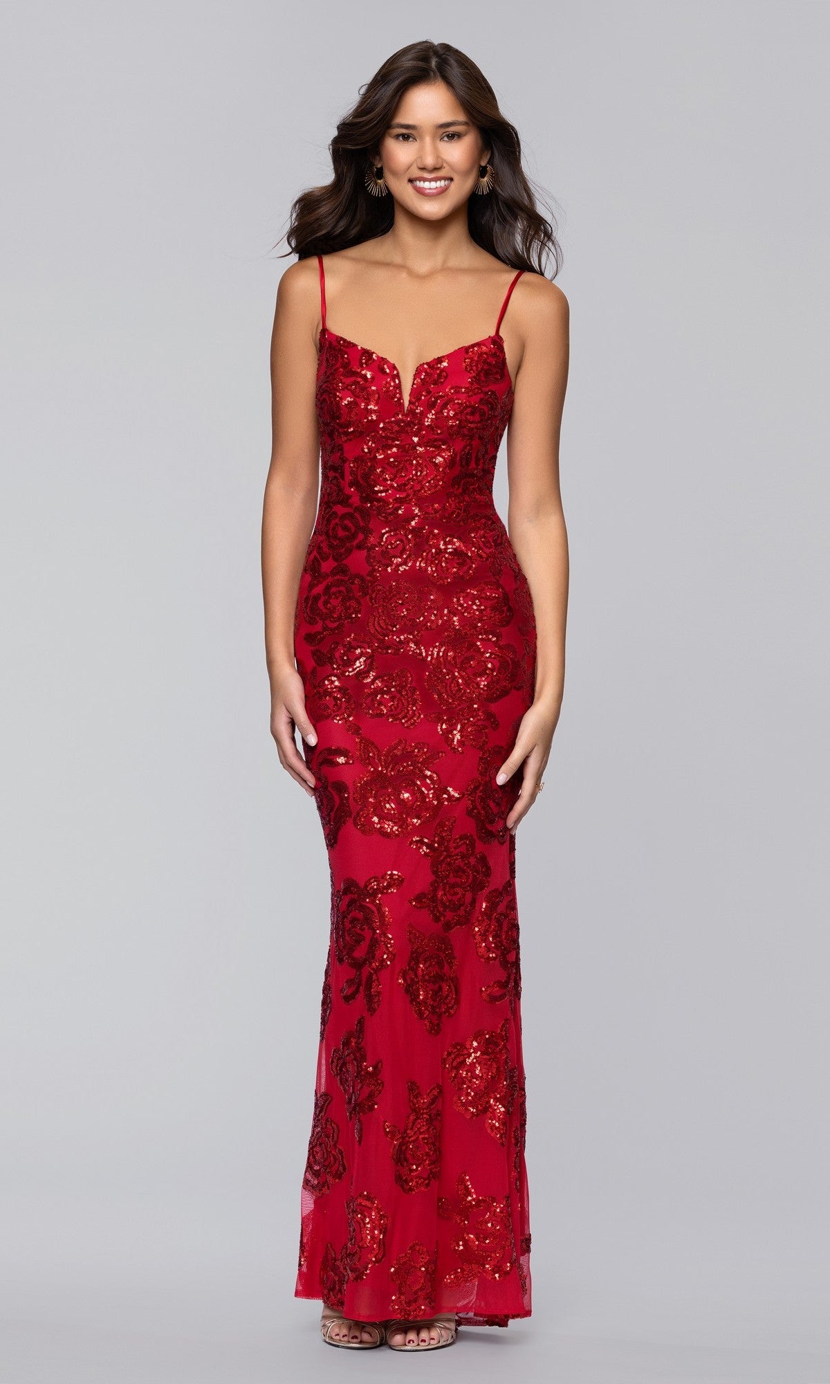 A woman smiles, wearing the Long Prom Dress: Blondie Nites 5905BN in red—a form-fitting sequin gown with thin straps and a fitted silhouette—posed against a plain gray background.
