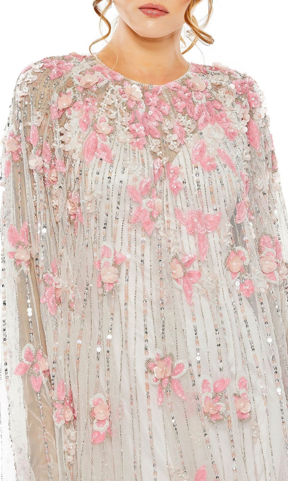 A woman wears the Mac Duggal 5917 Beaded-Cape Short Hoco Dress, featuring a sheer cape over a pink and white dress adorned with 3D floral and butterfly appliqués and vertical sequined stripes for a modern cocktail look.