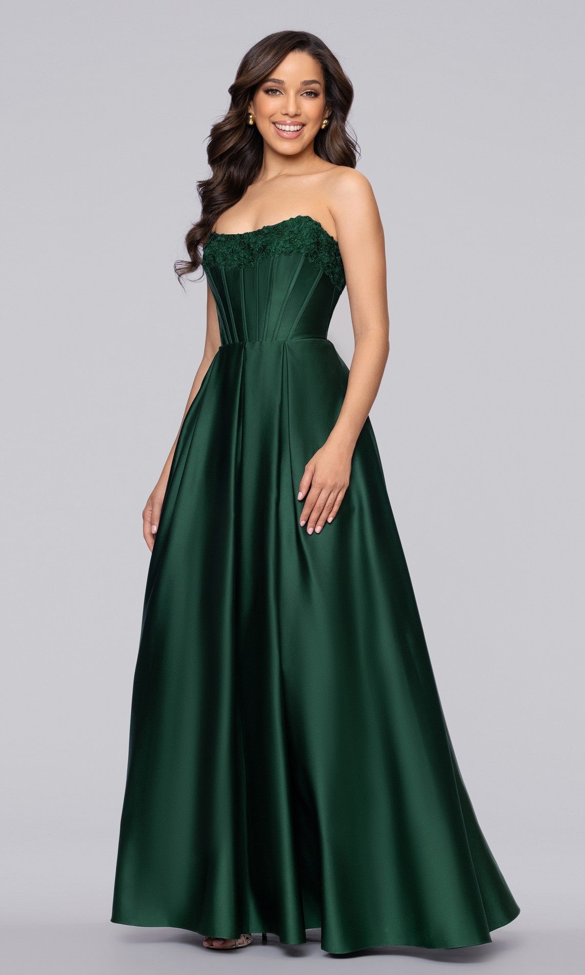 A woman wearing the Blondie Nites 5918BN long prom dress in hunter, featuring a strapless satin design with a fitted corset bodice and elegant lace detailing along the top.