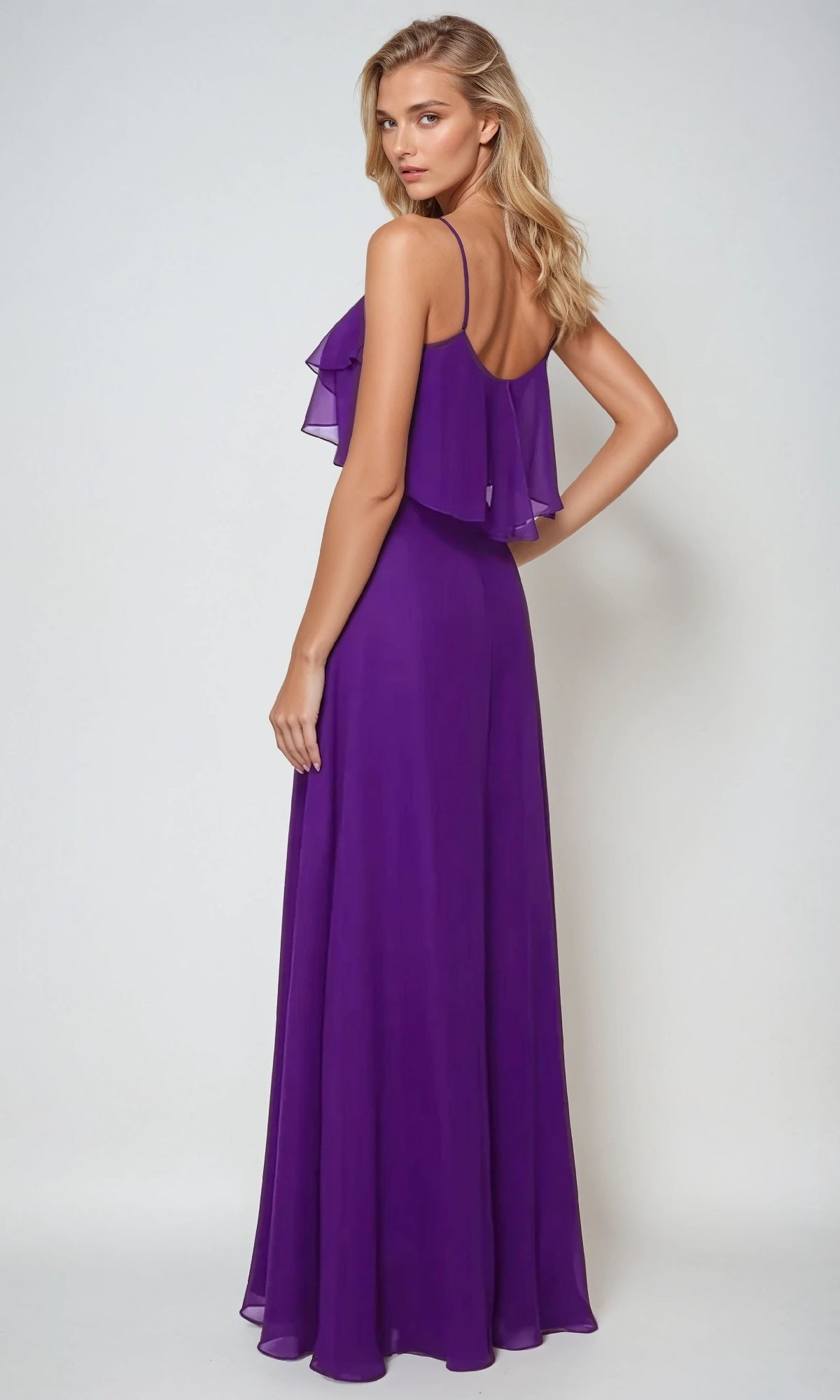A woman models the Juliet 591 long wedding-guest dress in purple, featuring a pop-over bodice and back ruffle detail, against a plain light background.