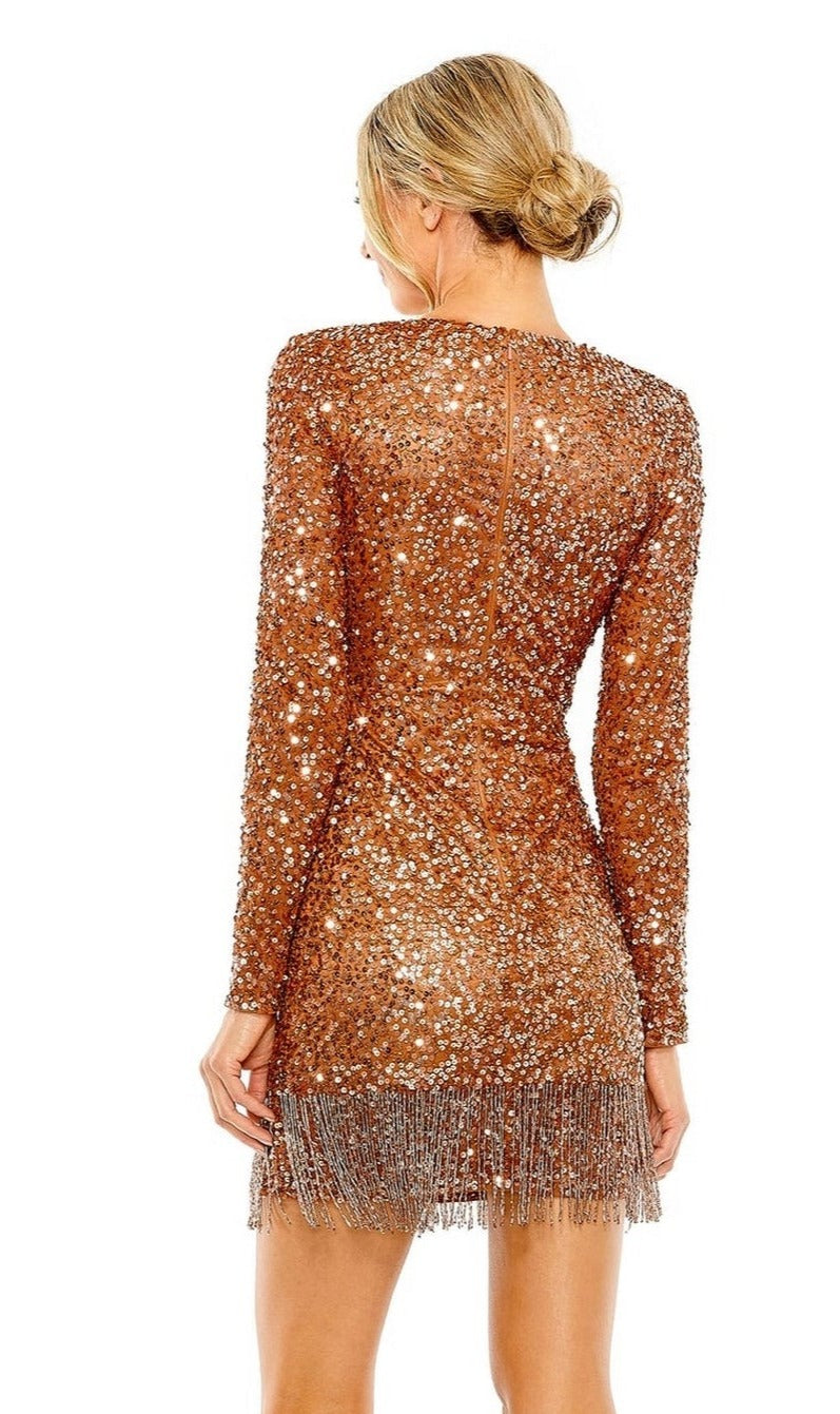 A woman with blonde hair in a low bun models the Short Beaded Copper Hoco Dress: Mac Duggal 5928, featuring fitted long sleeves, bronze sequins, and hem fringe, as she stands with her back to the camera.