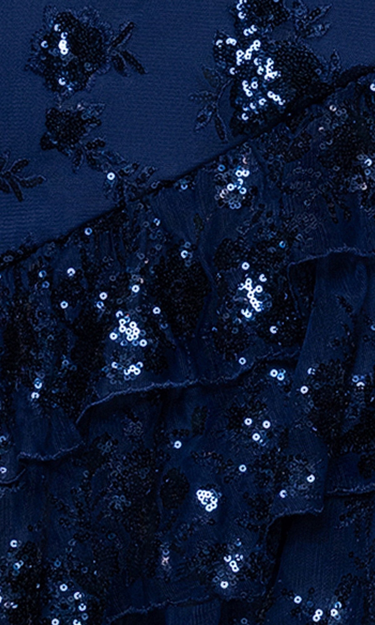 Close-up of the Long Prom Dress: Blondie Nites 5962BN in dark blue fabric with sequin embroidery, ruffled layers inspired by a tiered ruffle skirt, and a shimmering floral pattern.