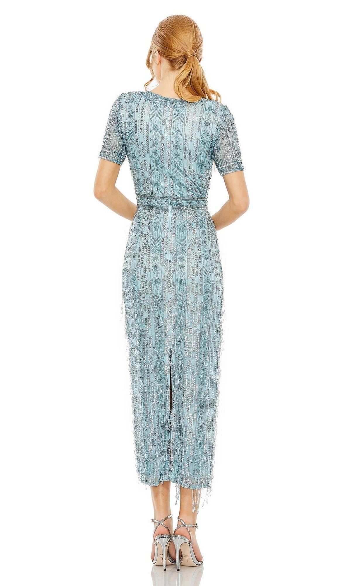 A woman with light brown hair in a ponytail wears the Mac Duggal 5980 Midi Fringe Wedding-Guest Dress and high-heeled sandals, shown from behind against a white background.