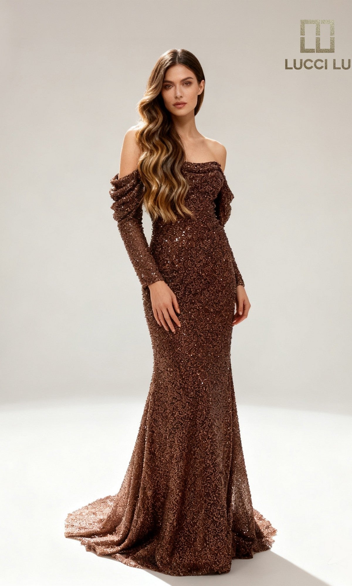 A woman poses in a studio wearing the fitted, off-the-shoulder Lucci Lu 6060 long formal dress in chocolate, adorned with sequins. The