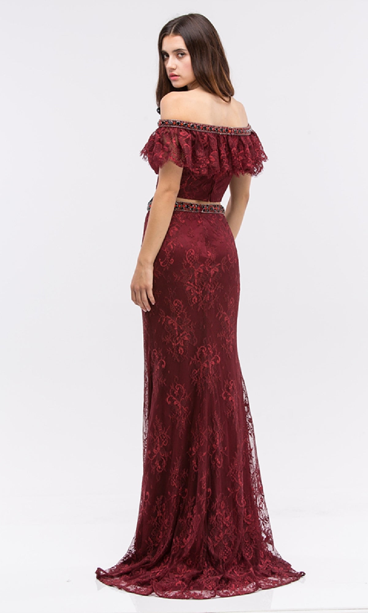 A woman poses sideways in the Eureka 6113 long formal dress, featuring an off-the-shoulder lace design, a fitted bodice, and floor-length mermaid silhouette, as she looks over her shoulder against a plain white background.