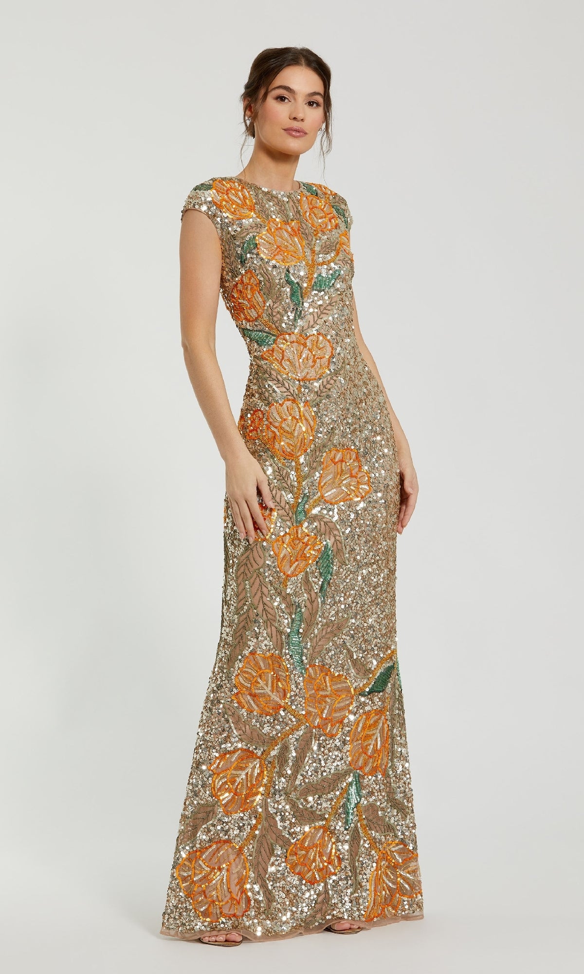 A woman wears the Mac Duggal 6121 long formal dress, a floor-length, fitted gown with short sleeves, gold sequin embellishments, and orange floral embroidery.