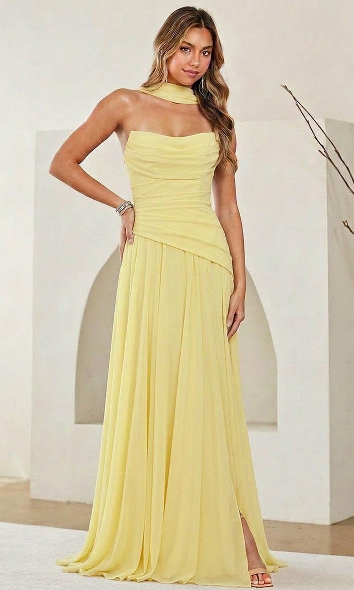 A woman stands indoors against a minimalist background, wearing the Amelia Couture 6133 Strapless Chiffon Prom Gown with a ruched corset bodice and matching neck scarf.