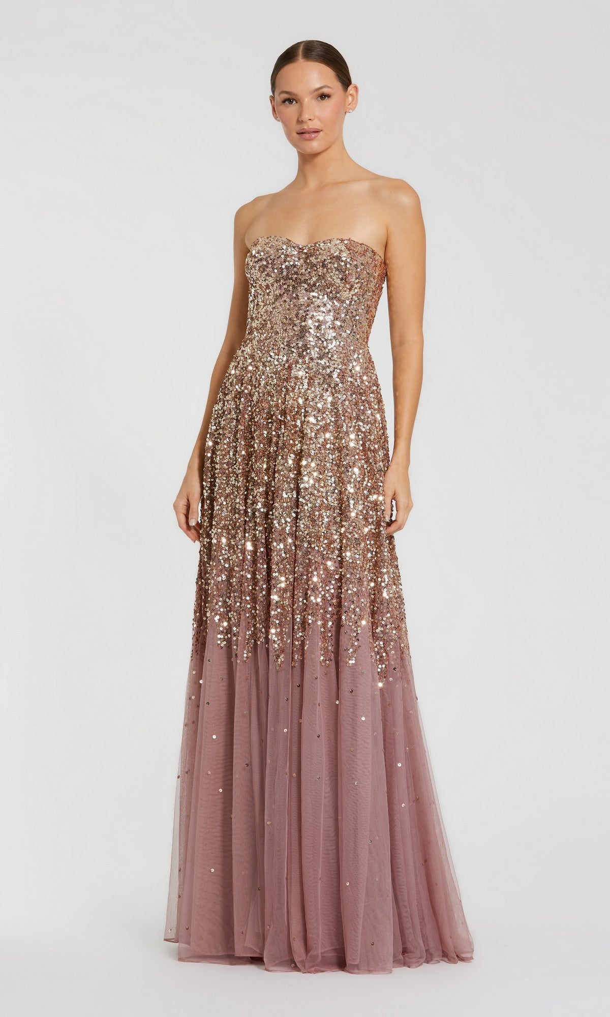 A woman stands gracefully against a plain white background, wearing the Mac Duggal 6144 long formal dress in Gold Amethyst—a striking strapless sequin gown featuring a gold embellished bodice and a floor-length ombre mauve tulle skirt.