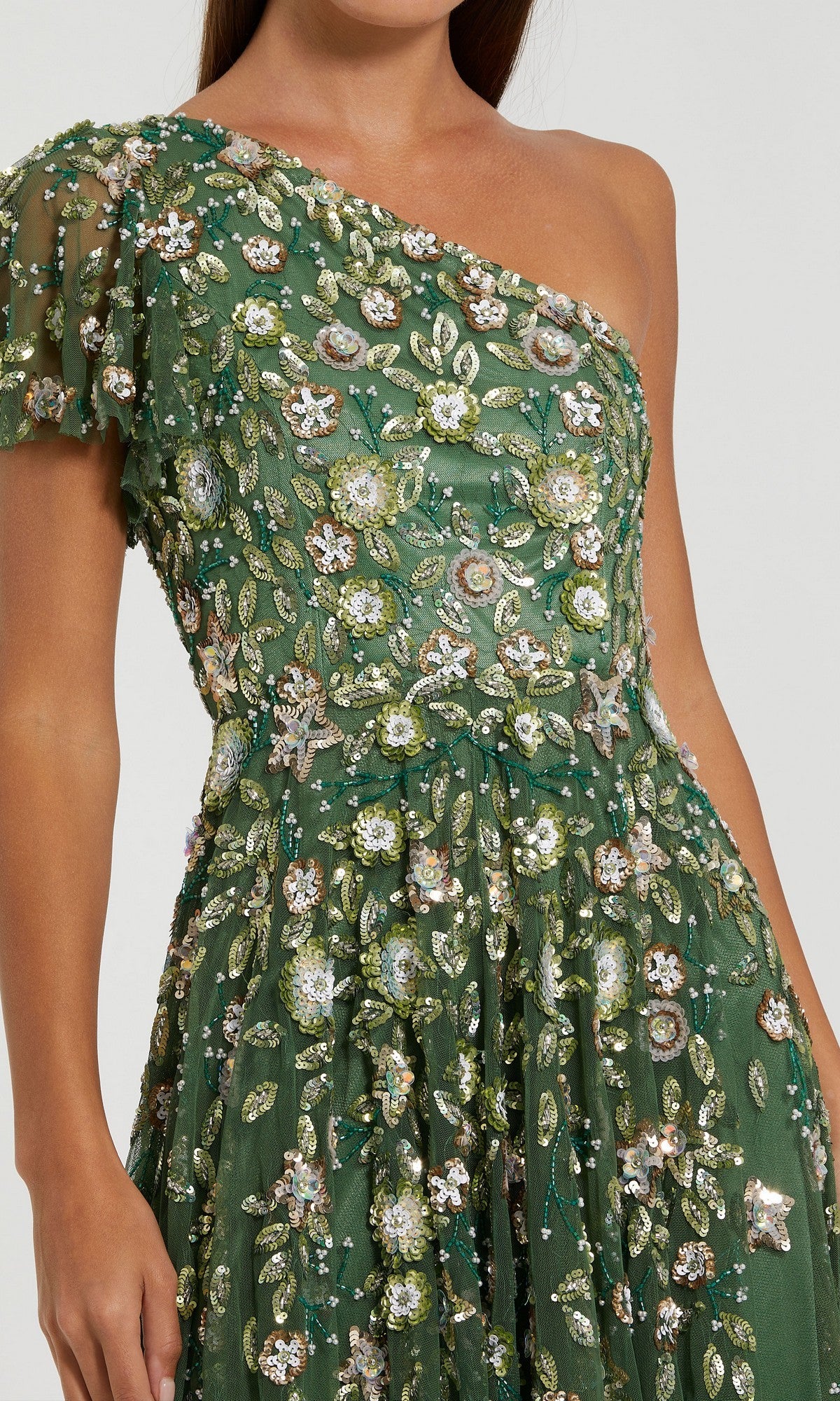 A woman wearing the Mac Duggal 6159 long formal dress in sage green, showcasing a one-shoulder design embellished with intricate floral and leaf embroidery and sparkling sequins.