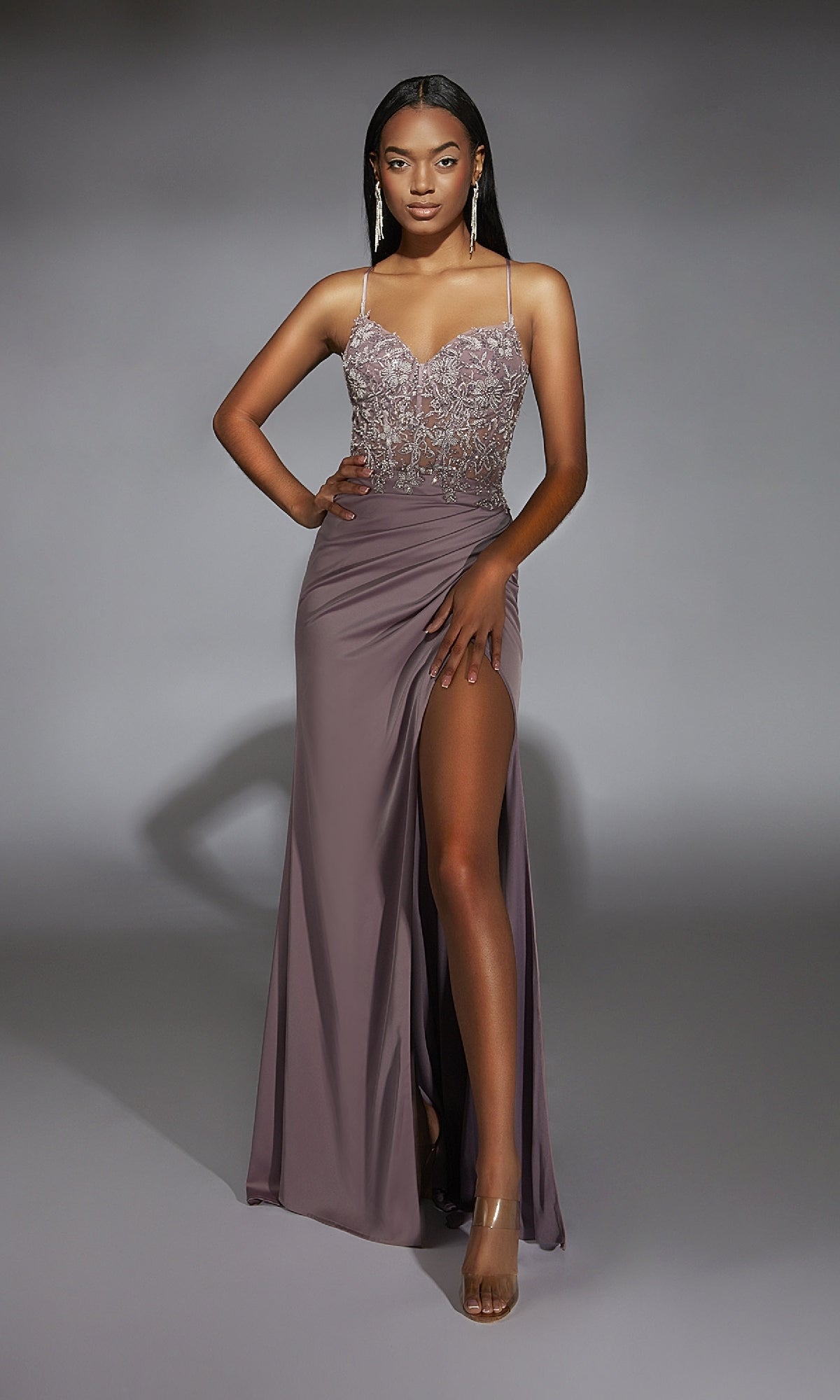 Woman wearing the Alyce 61741 Beaded-Lace-Corset Long Prom Dress, featuring a sleeveless mauve design with a beaded bodice and high slit, poses with one hand on her hip against a plain background.
