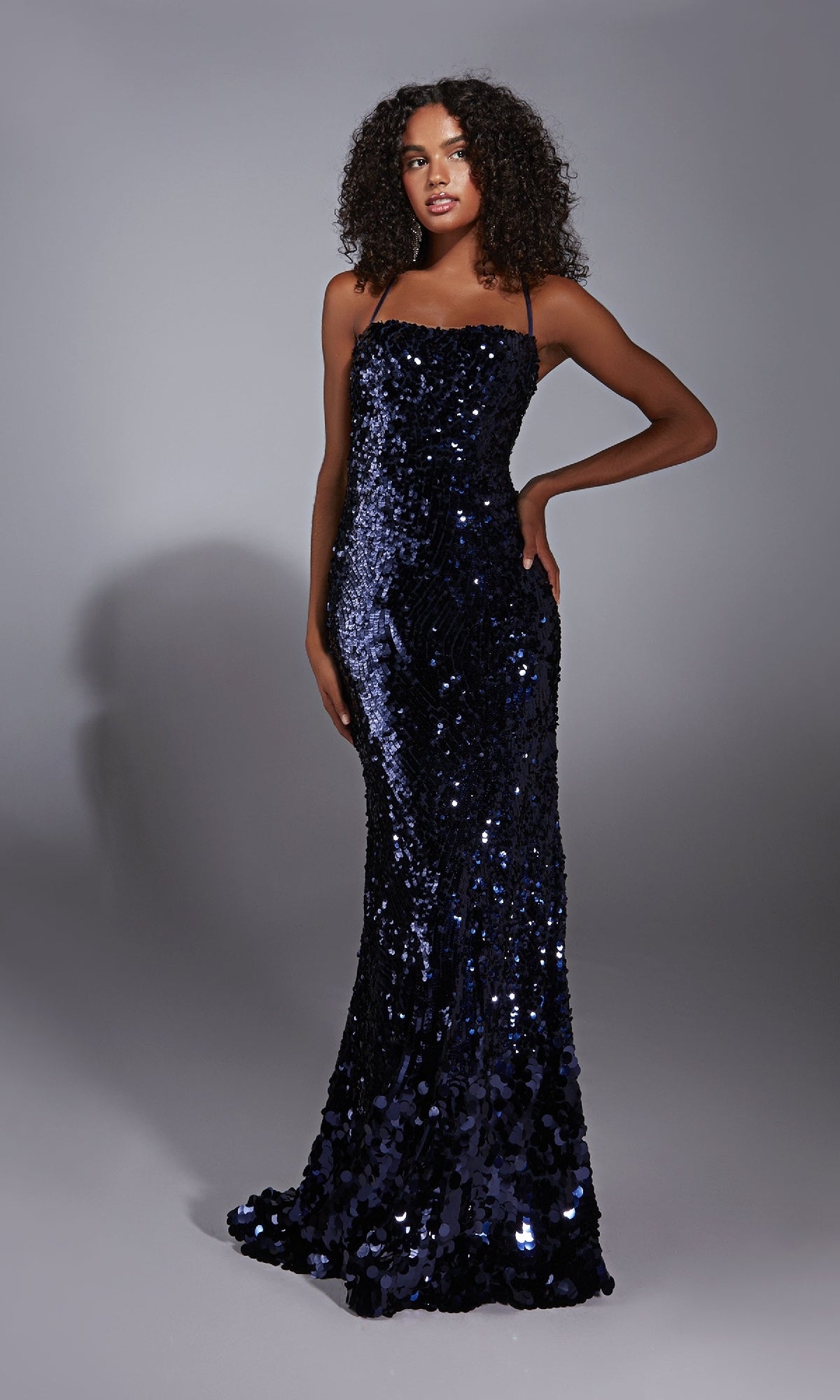 A woman poses against a plain gray background in the Alyce 61758 Strappy-Back Long Sequin Prom Dress, featuring thin straps and a fitted, floor-length silhouette.