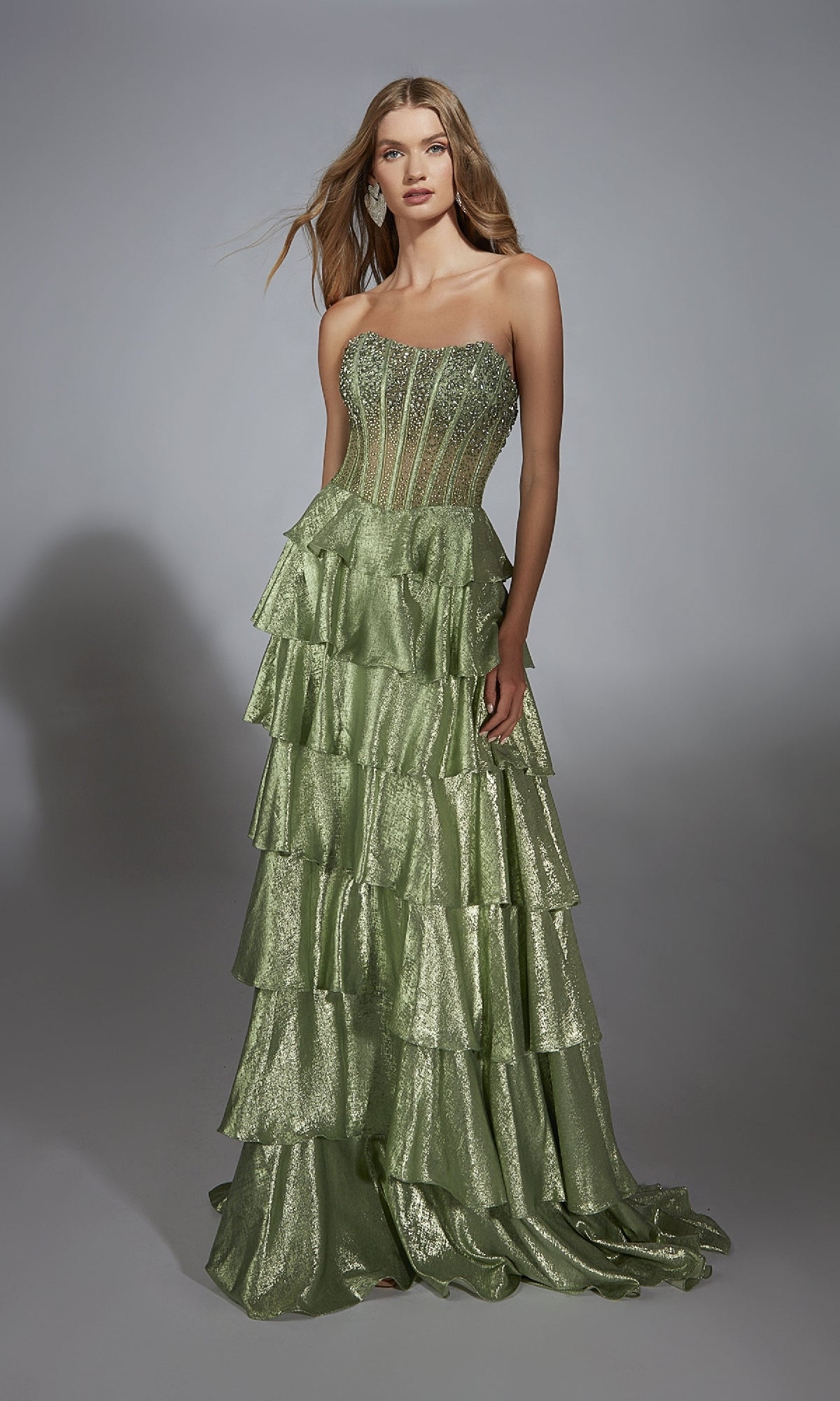 A woman models the Alyce 61783 long prom dress in light green, with a strapless embellished corset bodice and tiered A-line skirt, set against a plain gray background.