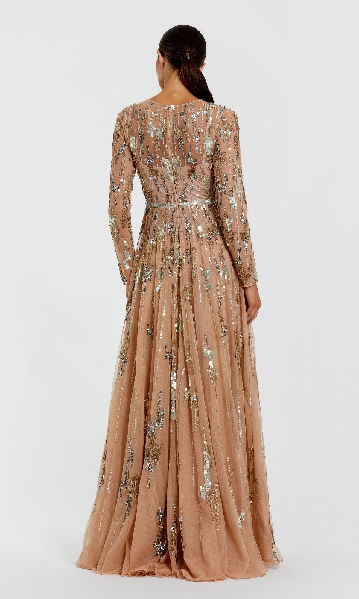 A woman wears the Mac Duggal 6181 Long Formal Dress, a peach-colored sequin evening gown with long sleeves, standing with her back to the camera against a plain white background.