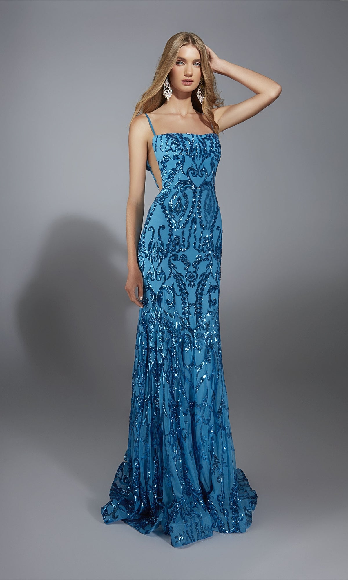 A woman wears the Alyce 61852 long prom dress, a sleeveless blue sequin gown with intricate patterns, standing against a plain gray background.