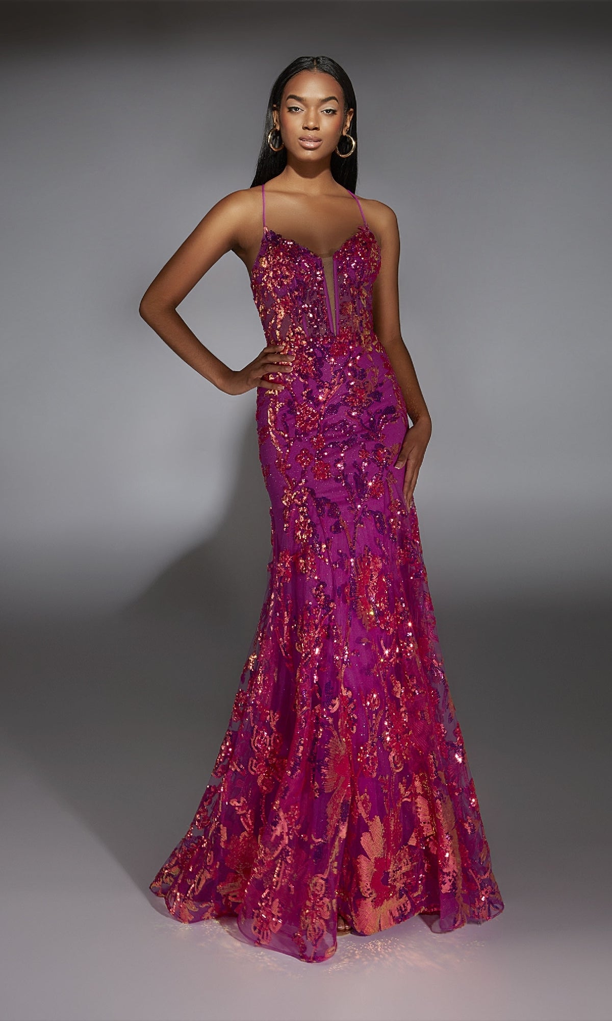 A woman poses confidently in a studio, wearing the Alyce 61854 Long Prom Dress—a magenta sequin gown with thin straps and a flared mermaid hem.