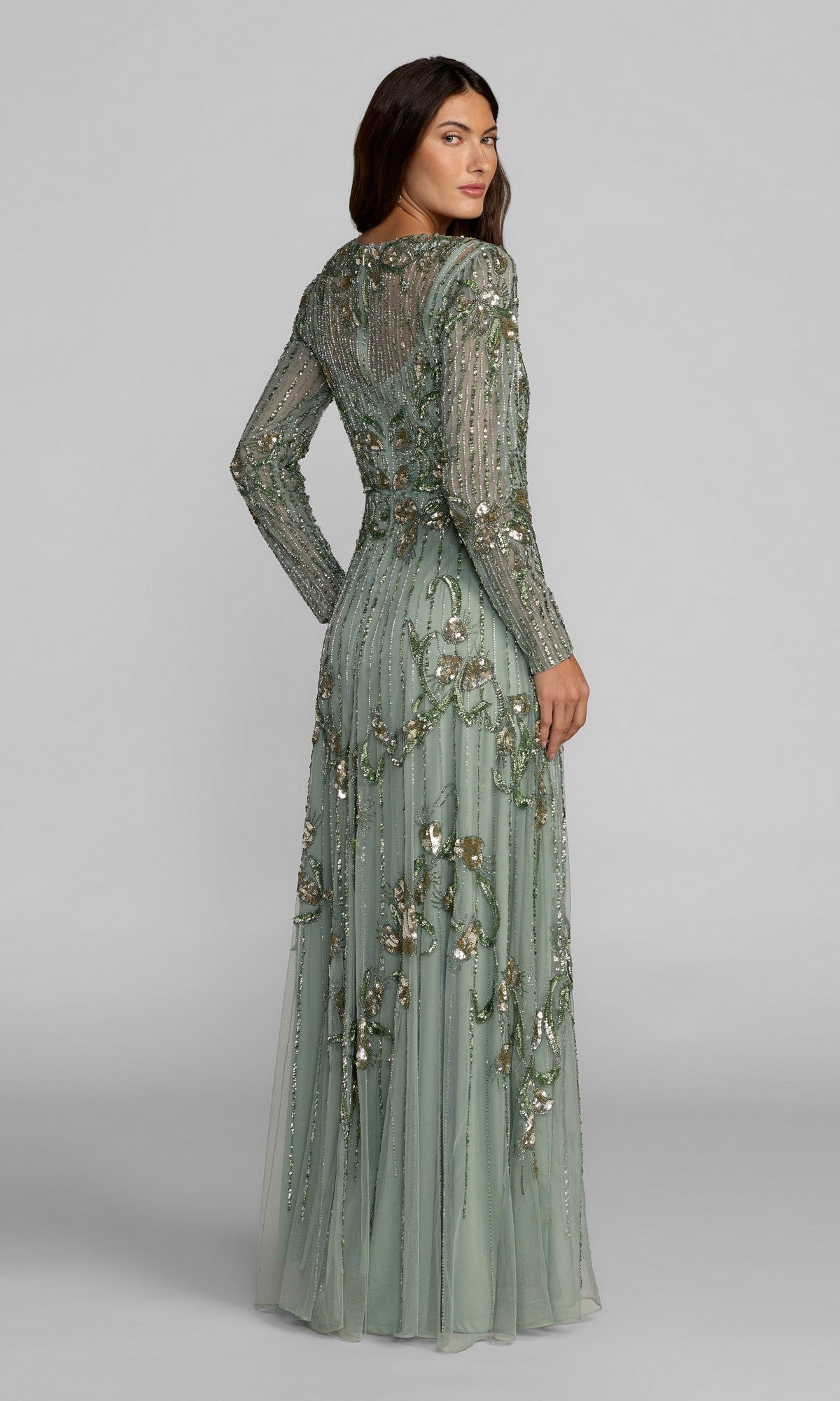 A woman in the Mac Duggal 6238 long formal dress in sage green, featuring intricate beadwork and delicate sequin embroidery, stands facing slightly away from the camera.