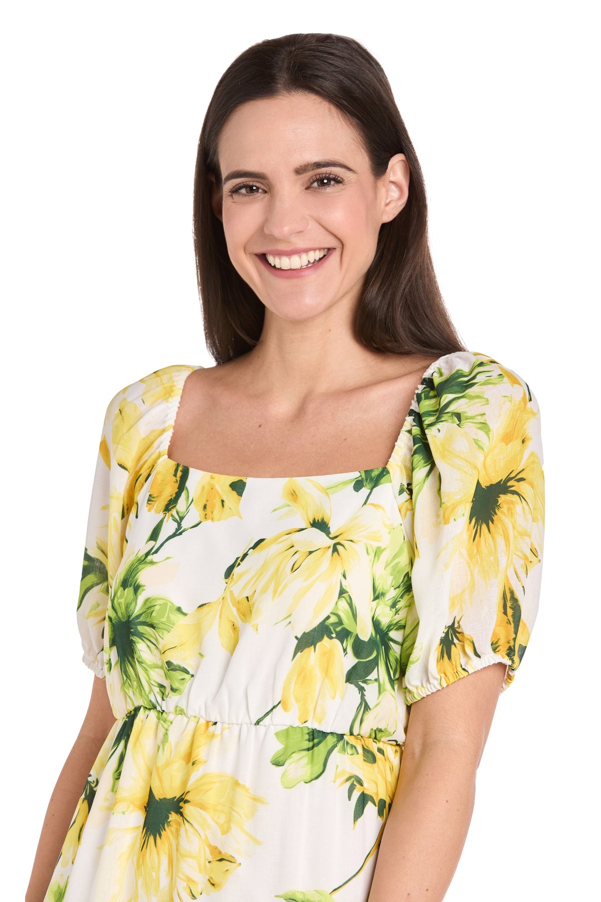 Smiling woman with long brown hair wears the Petite Midi Yellow Print Party Dress: R&M 6672P, featuring green floral accents, standing against a plain white background.