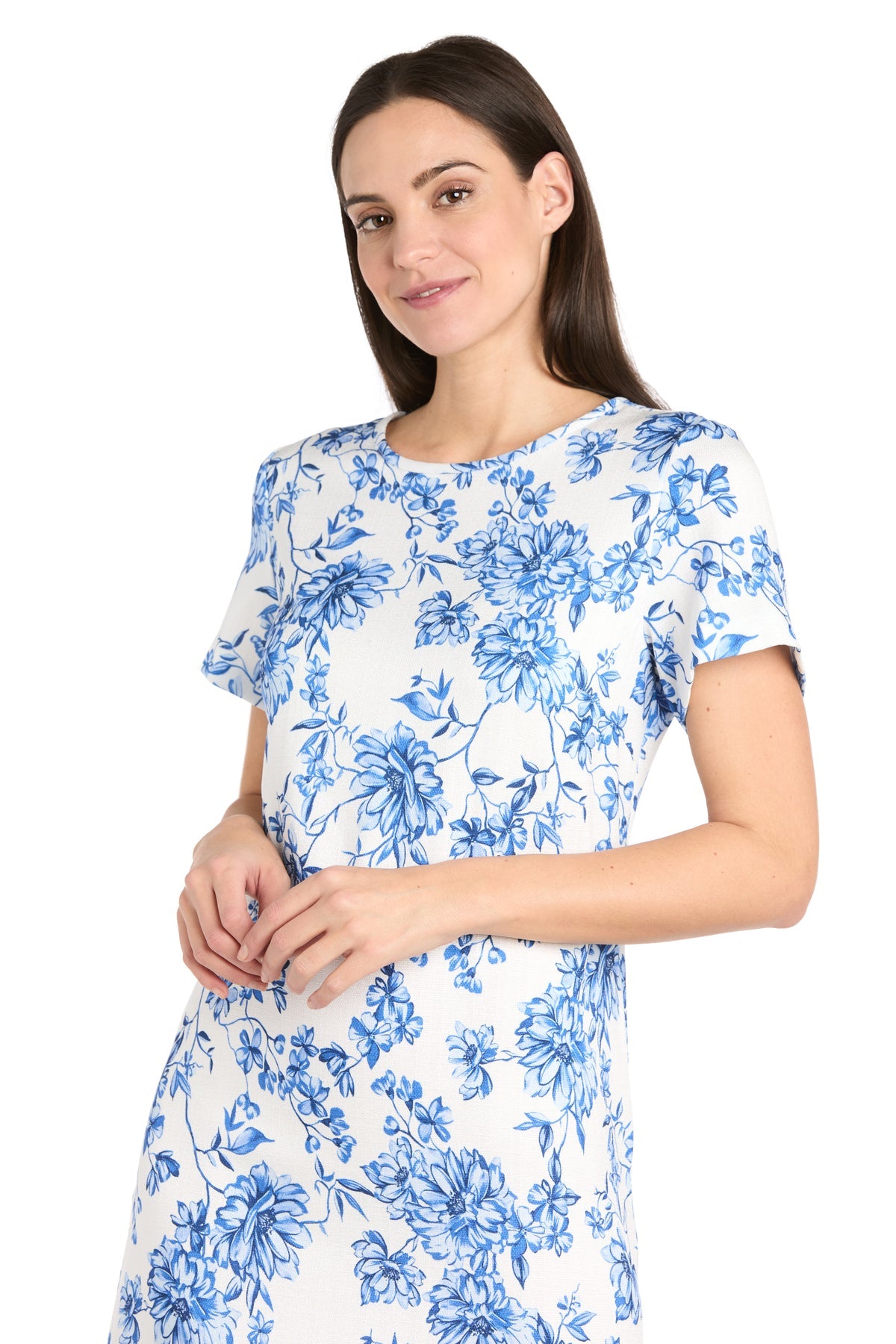 A woman smiles gently while wearing the Petite Print Party Dress: R&M Richards 6674P, featuring a casual blue floral linen design, standing against a plain white background.