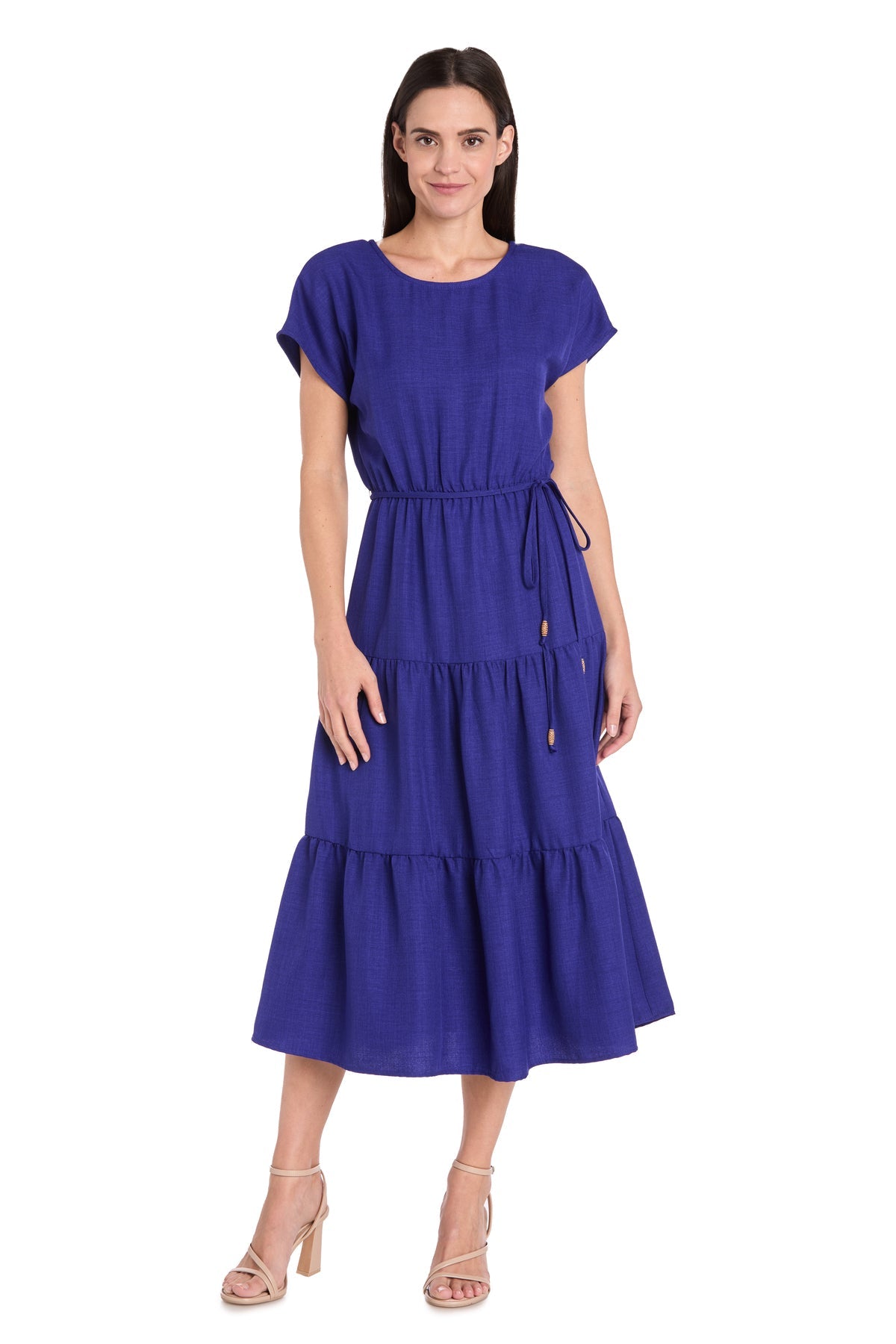 A woman wears the R&M Richards 6680 Tea-Length Blue Party Dress with short sleeves, tiered layers, and a drawstring waist, paired with nude heeled sandals.
