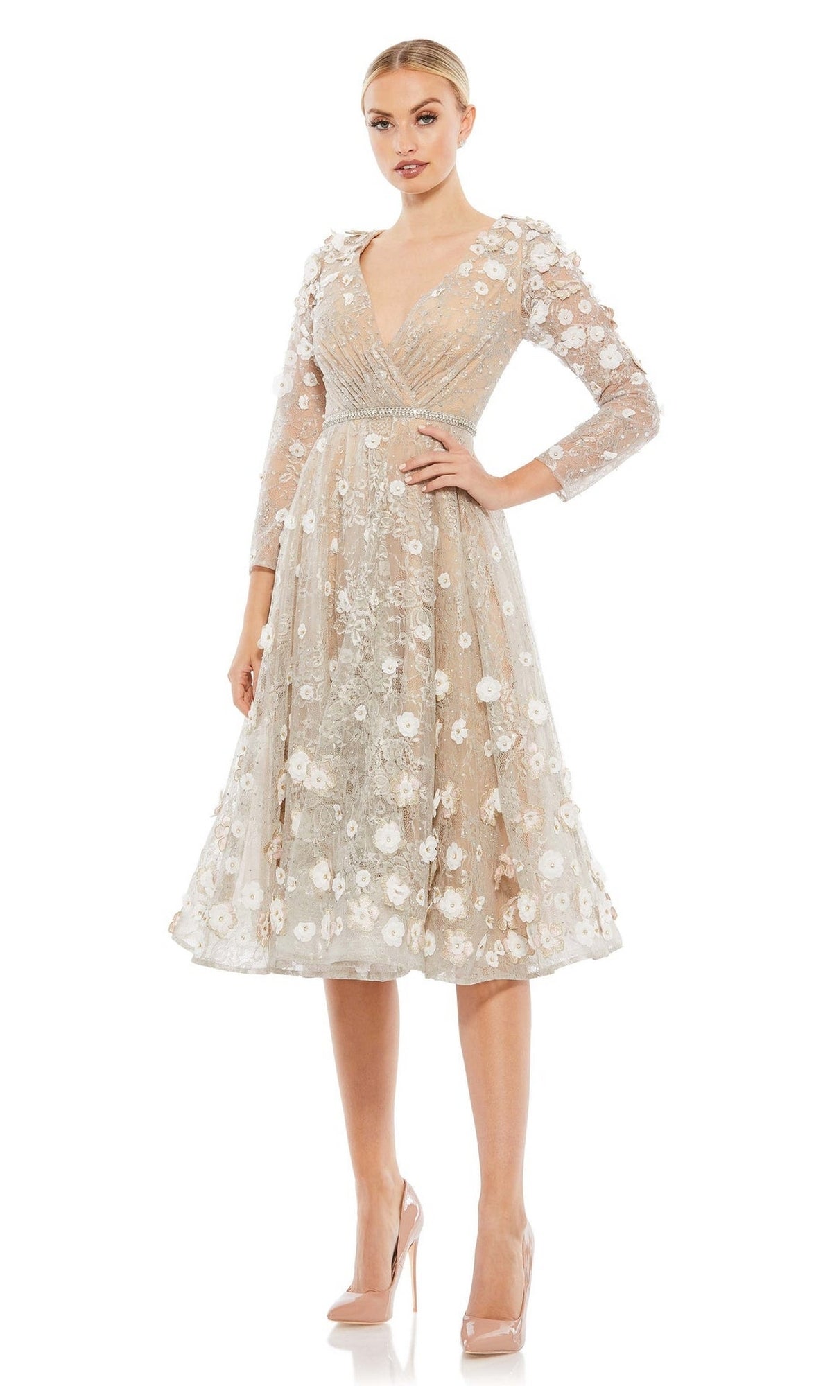 A woman stands against a white background wearing the Mac Duggal Short Wedding Guest Dress 67387—knee-length, sheer beige with white floral appliqué, V-neckline, three-quarter sleeves—and nude high heels.