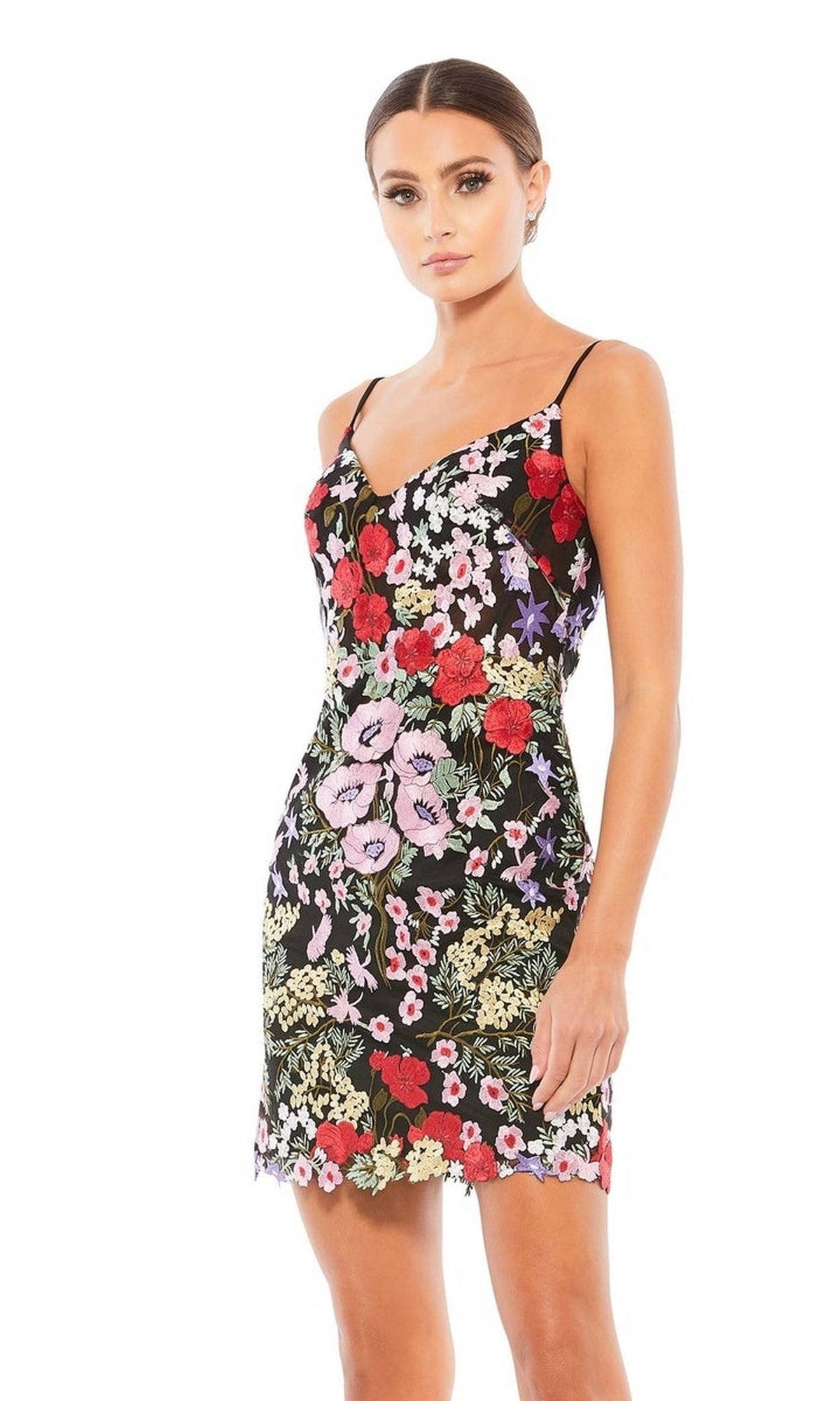 A woman stands against a plain white background wearing the Mac Duggal 67459 short floral-print party dress, featuring a strappy back and vibrant floral embroidery.