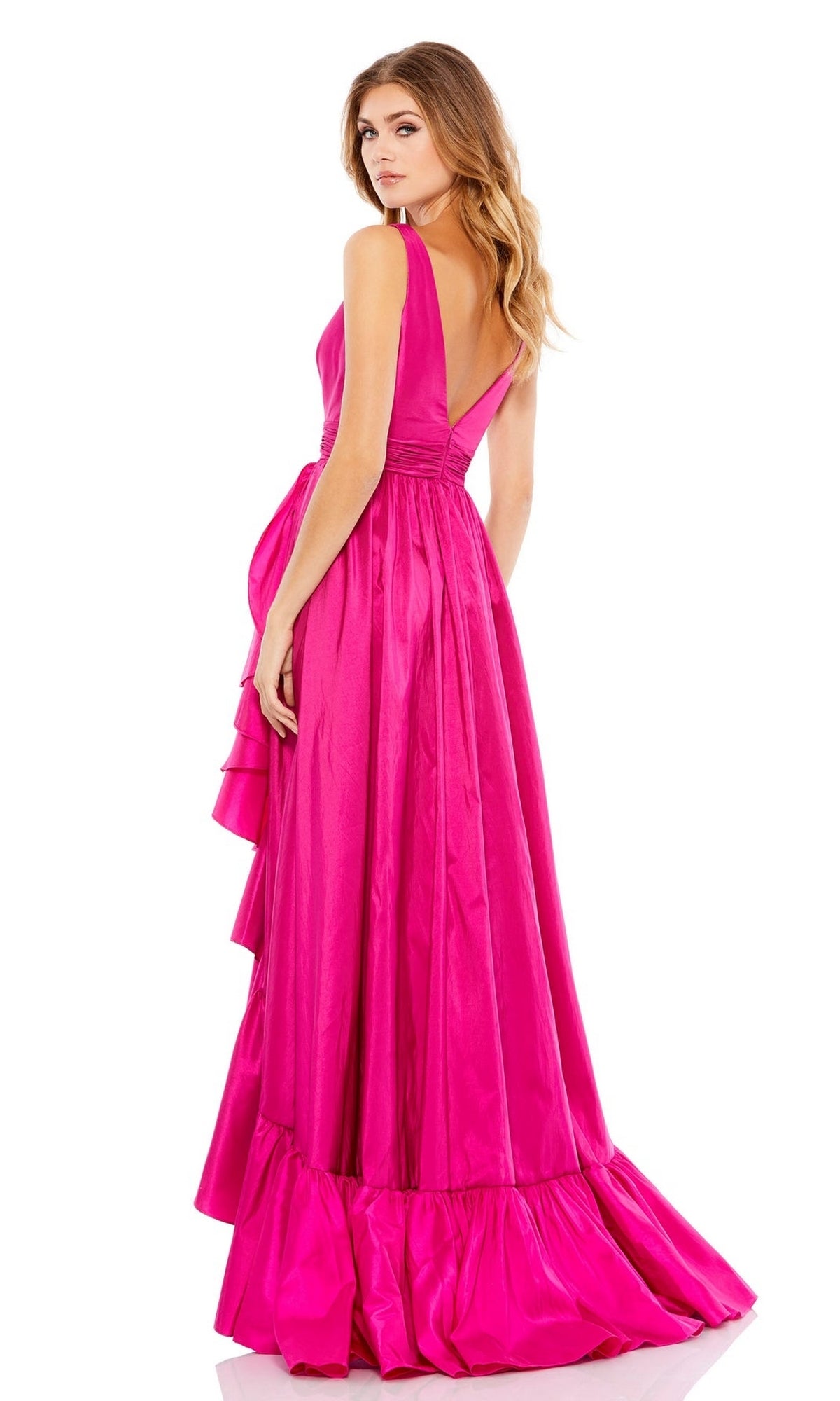 Woman models the Mac Duggal 67835 Long Ruffled Formal Dress—a floor-length, bright pink gown with a fitted bodice, deep V-back, ruffled side detail, and flared hem—as she stands looking over her shoulder.