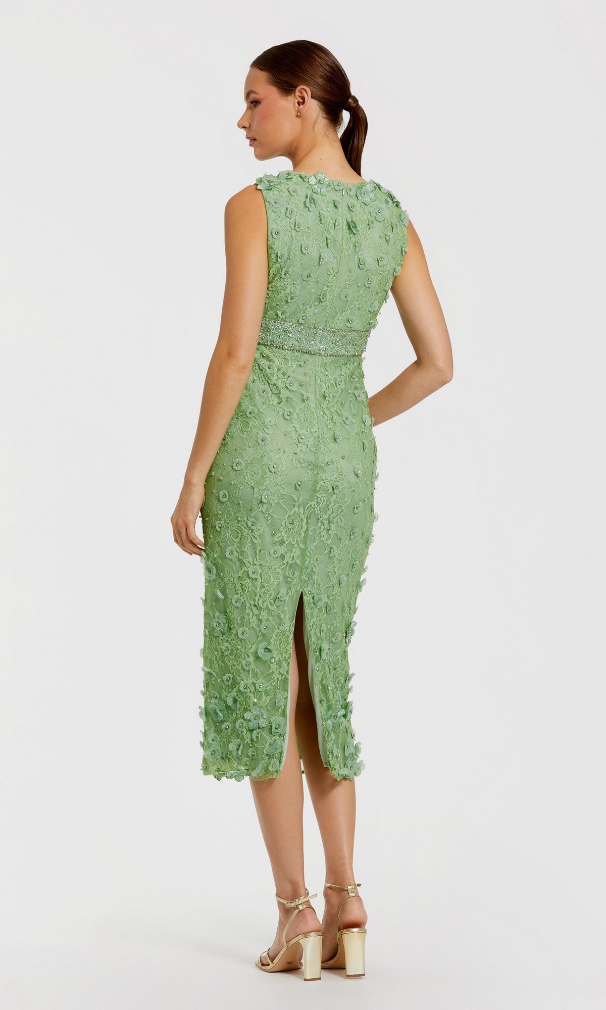 A woman stands with her back to the camera against a white background, wearing the Mac Duggal 67853 knee-length party dress—sleeveless, light green, and adorned with floral embellishments.