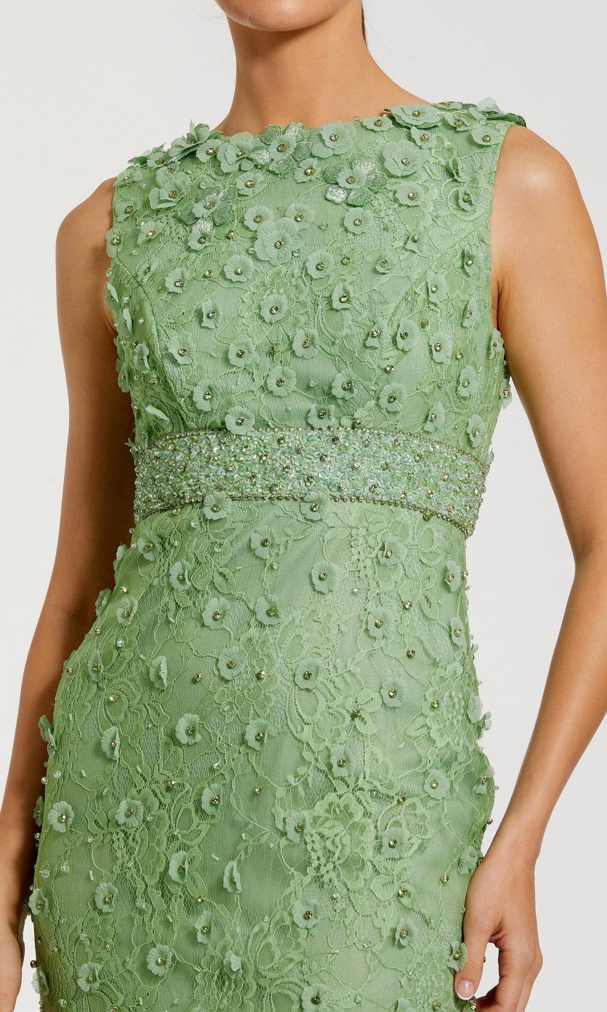 A woman wearing the Mac Duggal 67853 Knee-Length Party Dress, a sleeveless light green lace midi dress with floral appliqué and beading at the waist.
