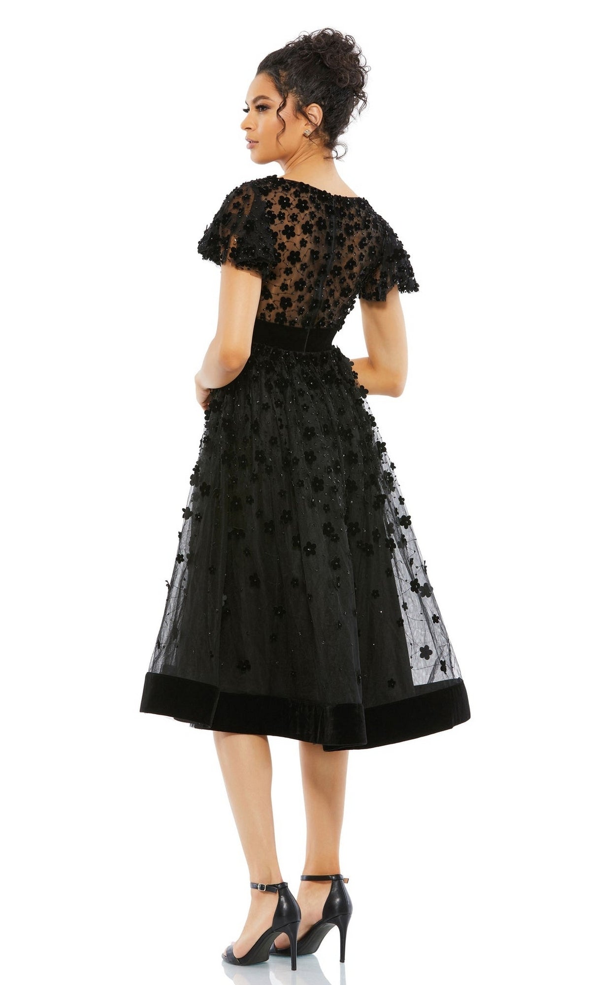 Woman in profile wearing the Mac Duggal 67854 Floral Midi Wedding Guest Dress, a vintage-style black floral embellished piece with short sleeves, paired with ankle-strap high heels.