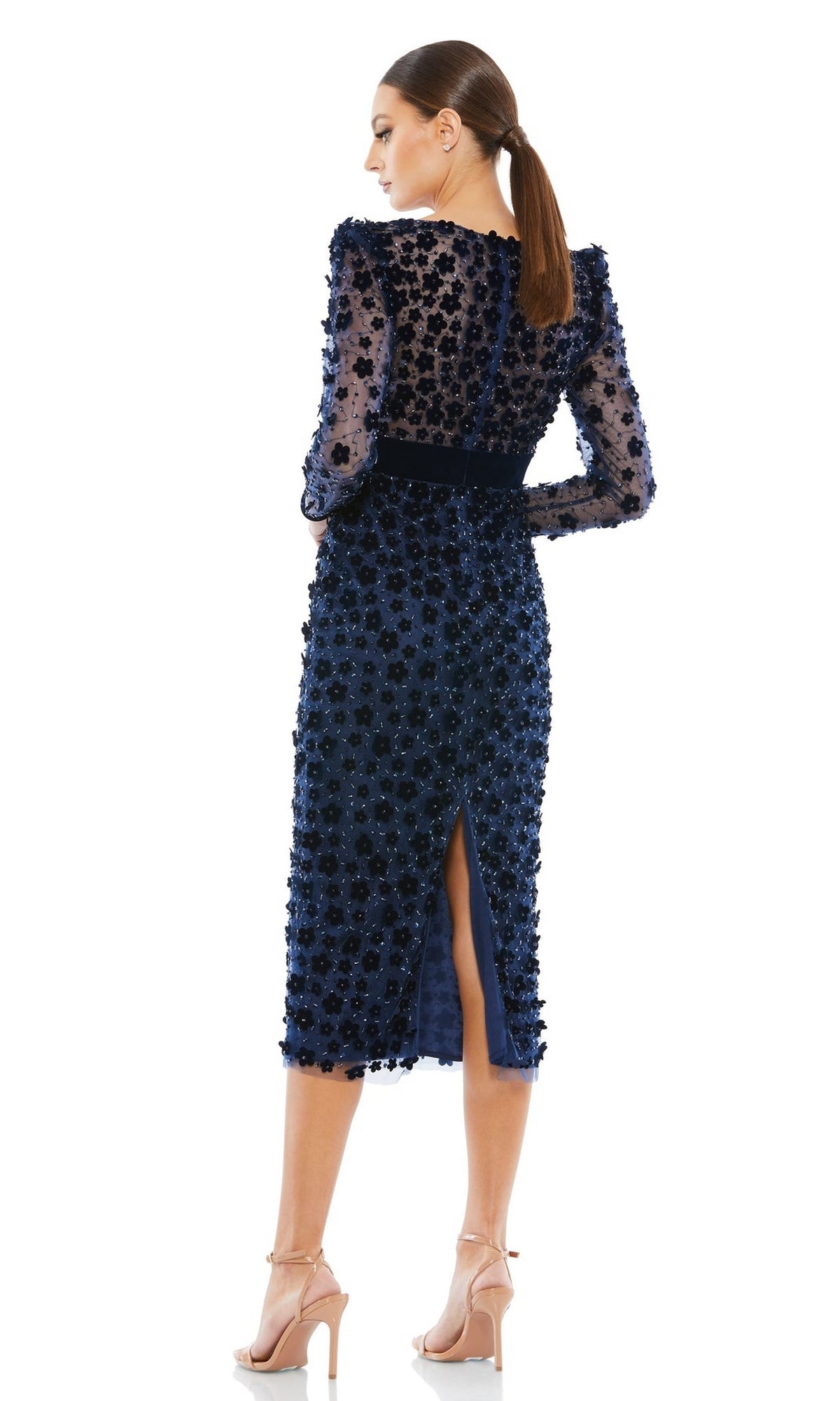 Wearing the Short Wedding Guest Dress 67856 by Mac Duggal—a navy blue, long-sleeved, knee-length floral embellished dress with a back slit—a woman in nude heels poses with her back to the camera, ideal for semi-formal events.