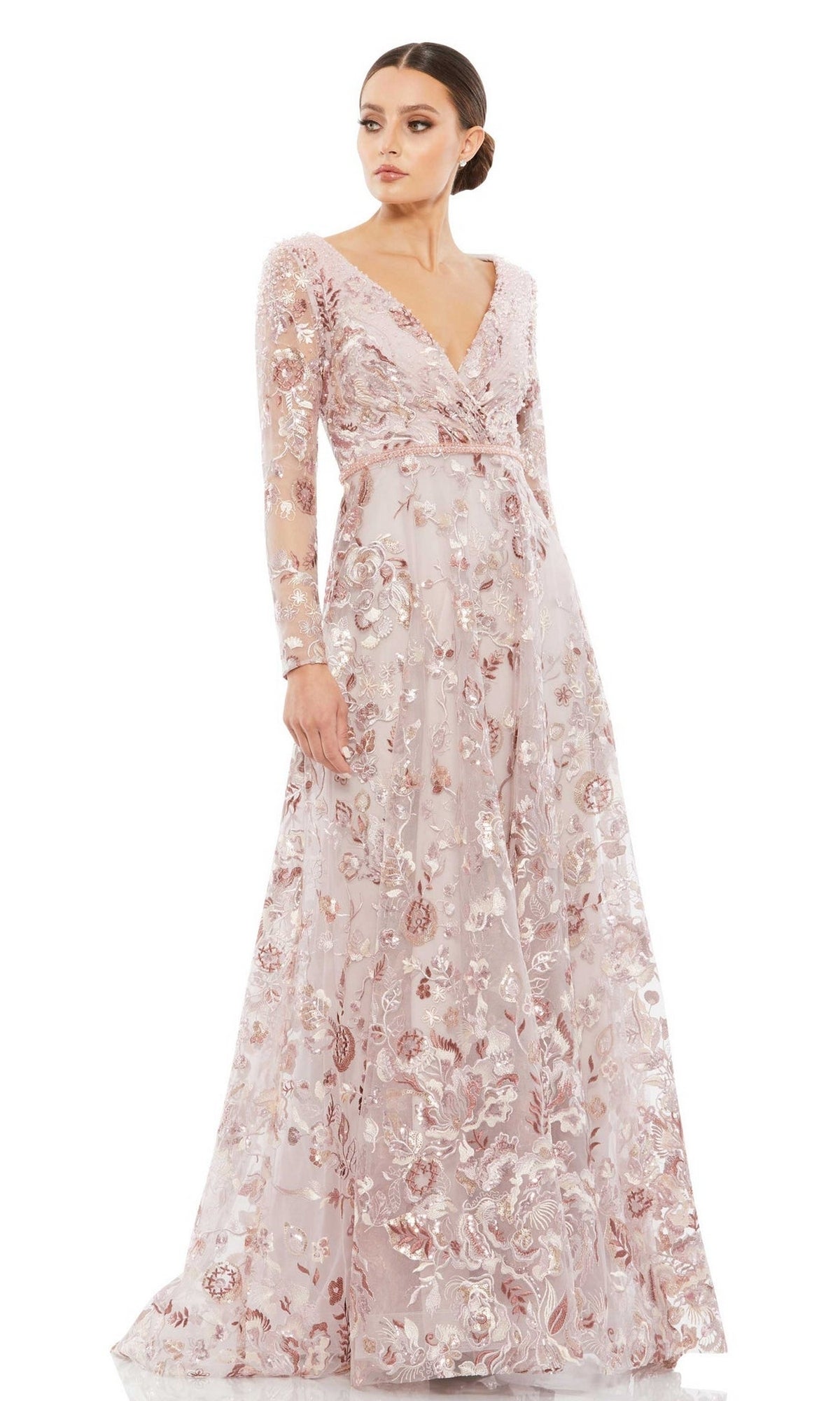 A woman wears the Mac Duggal 67869 Long Sleeve Lace Formal Dress, a long light pink evening gown with floral embroidery, standing against a plain background.