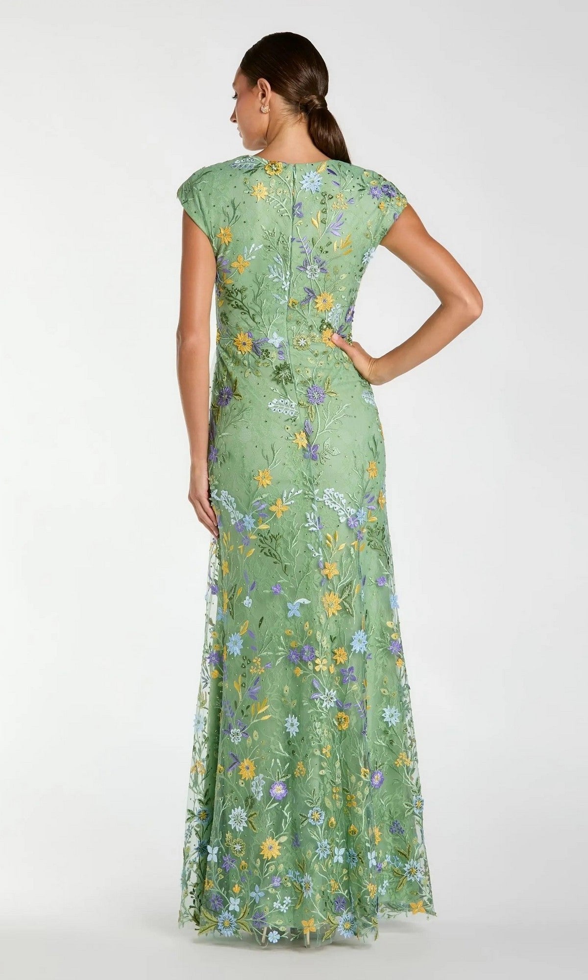 A woman stands with her hand on her hip, wearing a Mac Duggal 67882 cap sleeve long blue formal gown, viewed from the back.