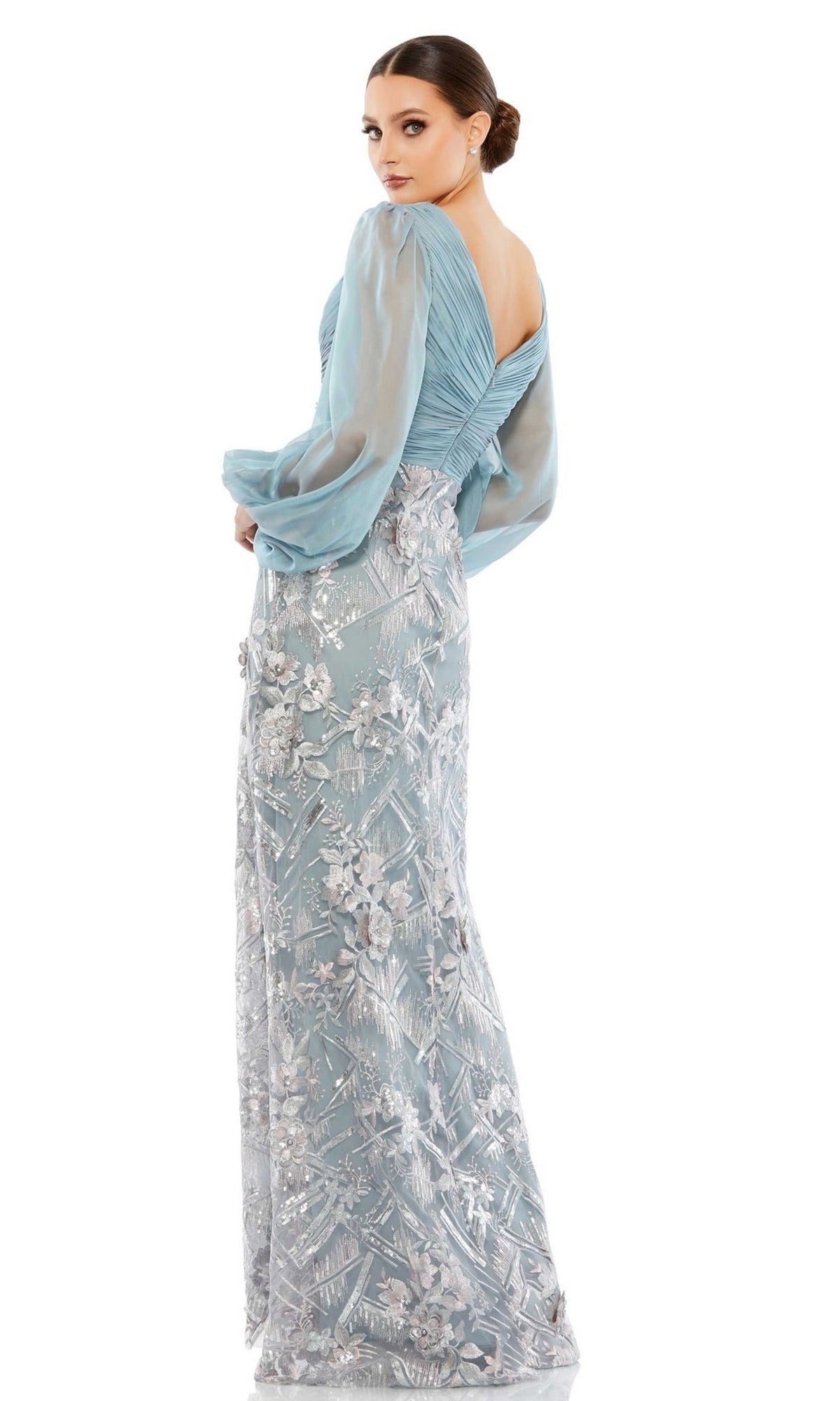 A woman stands against a white background wearing the Mac Duggal Long Formal Dress 67886 in slate blue, featuring sheer puff sleeves and a floral lace overlay on the floor-length skirt.