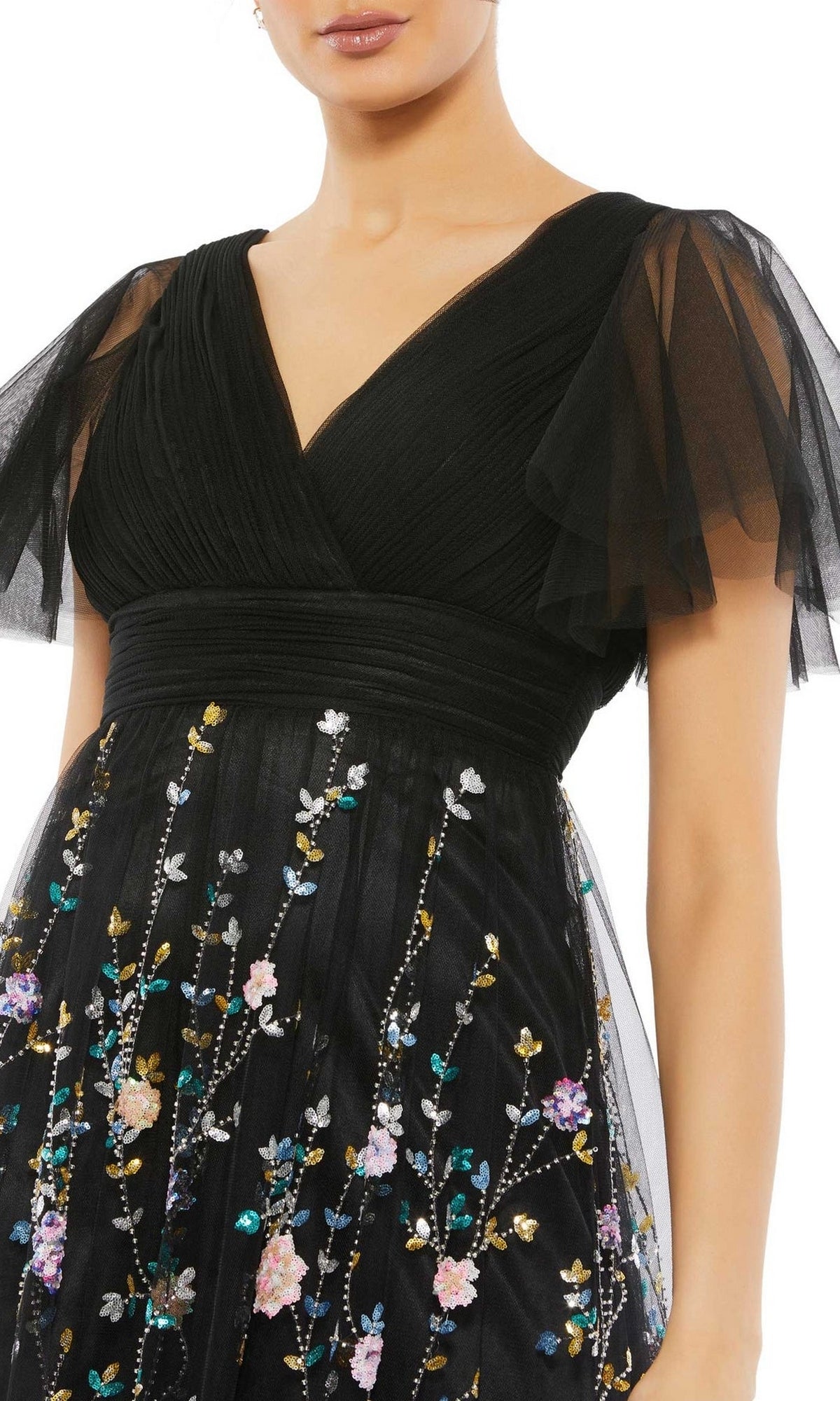 A woman wears the Black Long Floral Formal Dress: Mac Duggal 67889, featuring sheer flutter sleeves and a skirt adorned with multicolored floral embroidery.