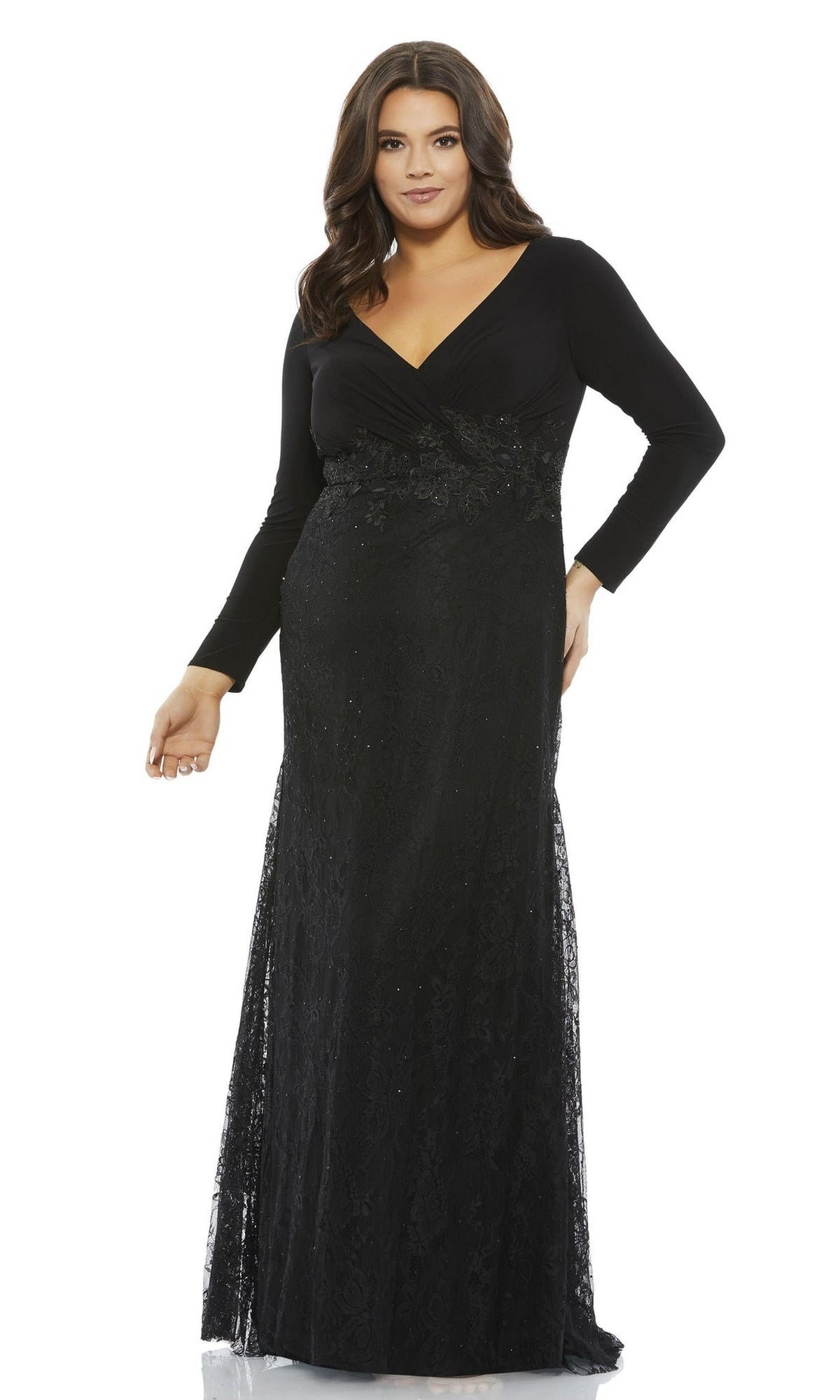 A woman wearing the Long Plus-Size Prom Dress 67896 by Mac Duggal: a floor-length black trumpet gown with lace long sleeves, a V-neckline, and floral detailing at the waist.