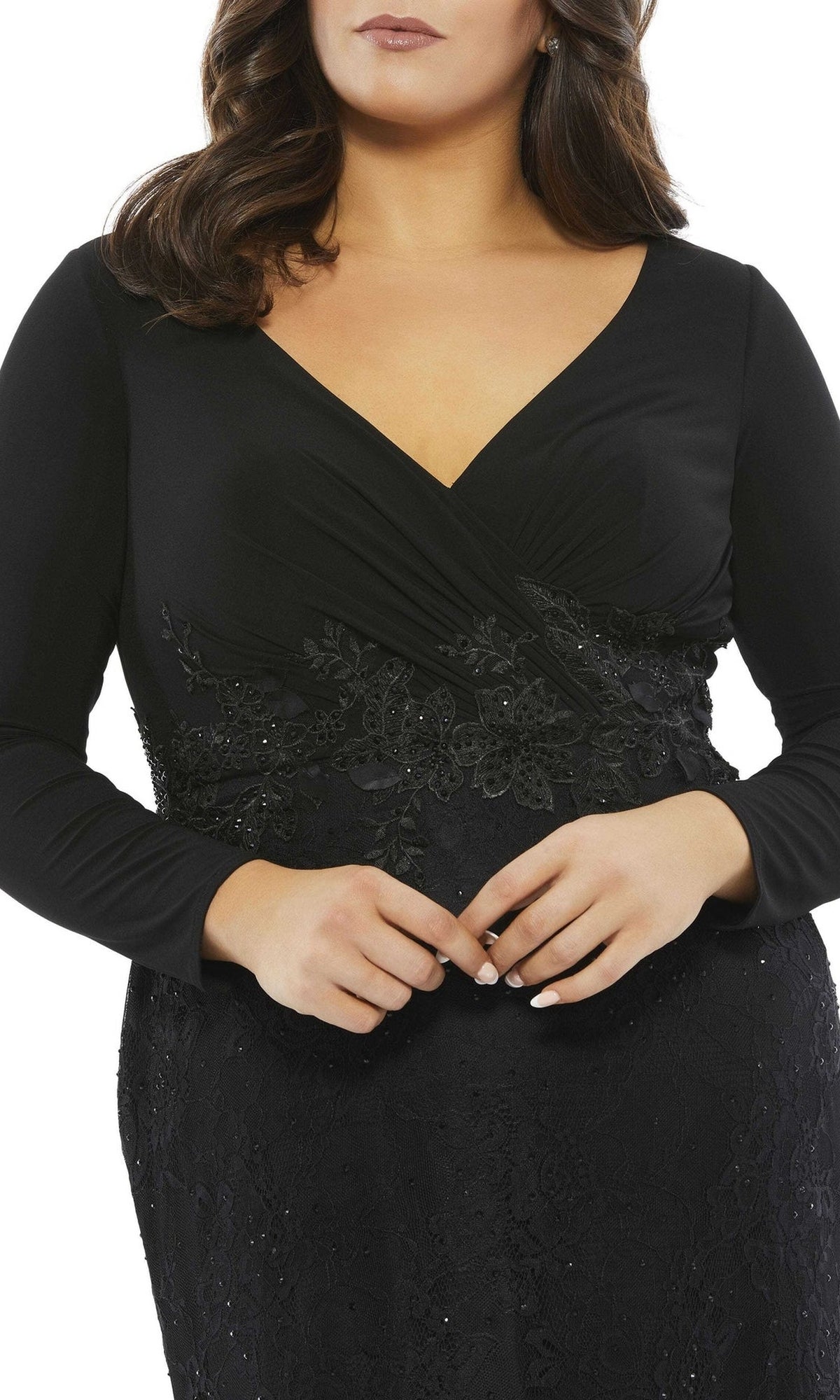 A woman wears the Long Plus-Size Prom Dress 67896 by Mac Duggal, a black trumpet gown with lace long sleeves and sequin waist details, shown from shoulders to hips.