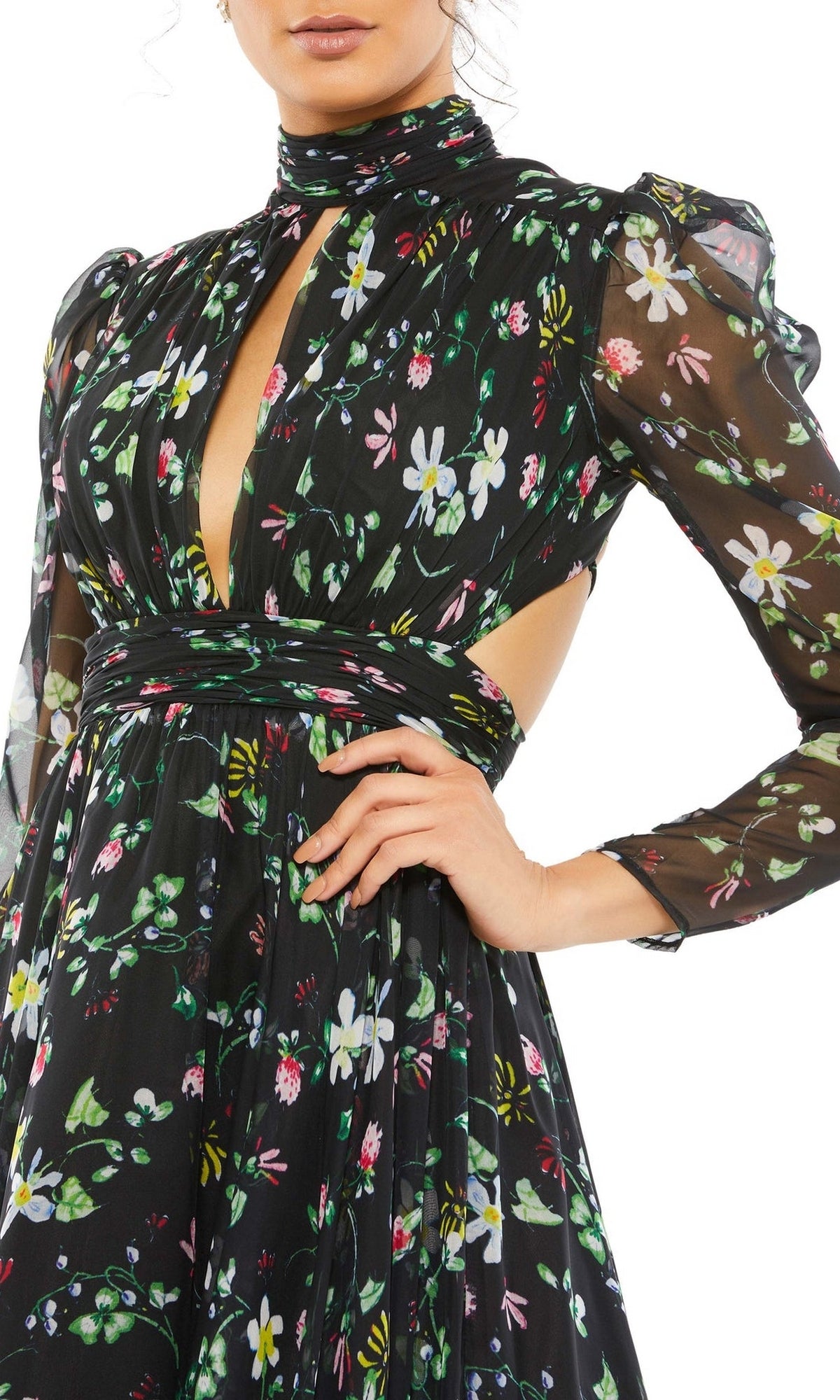 A woman poses with one hand on her hip, wearing the Mac Duggal 67942 Long Black Print Formal Dress featuring sheer long sleeves, a high neck, cut-out sides, and a black floral print.