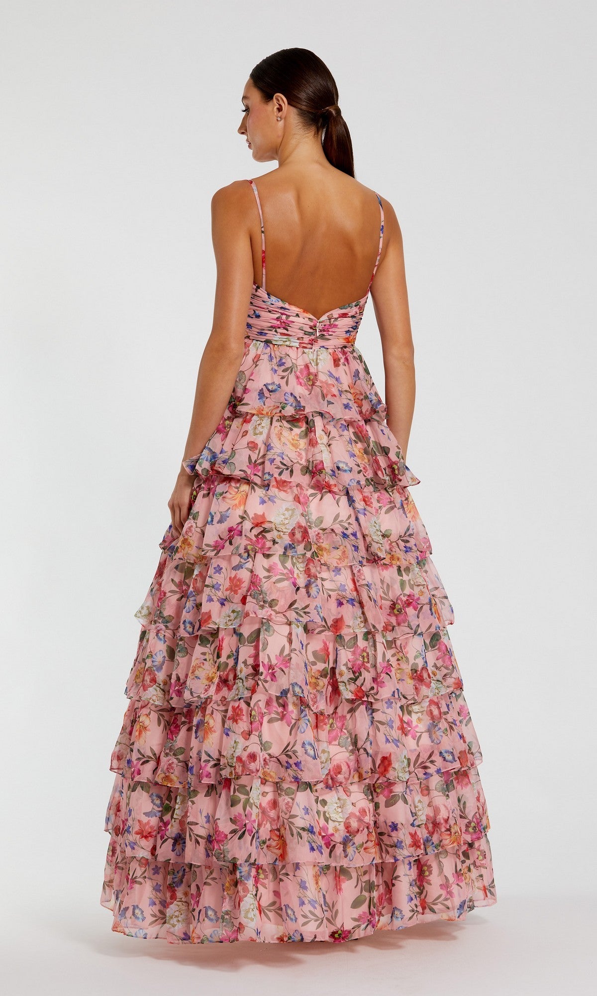 A woman faces away in the Mac Duggal 67966 Violet Print Prom Ball Gown, a sleeveless, floor-length dress featuring multiple ruffled tiers and a vibrant floral pattern.