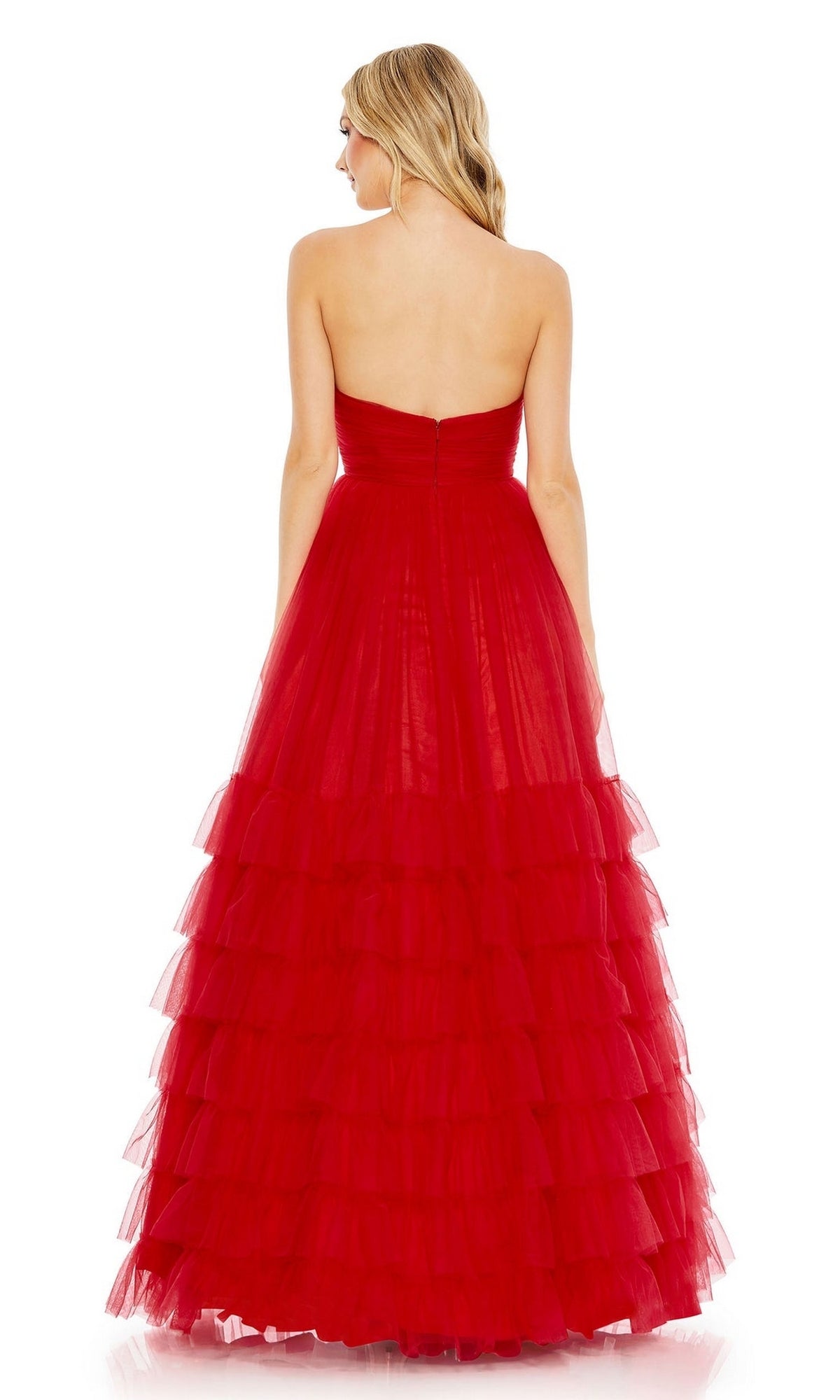 A woman stands facing away, wearing the Mac Duggal Long Formal Dress 67999—a strapless, floor-length gown with an empire waist and layered red tulle ruffles flowing gracefully behind her.