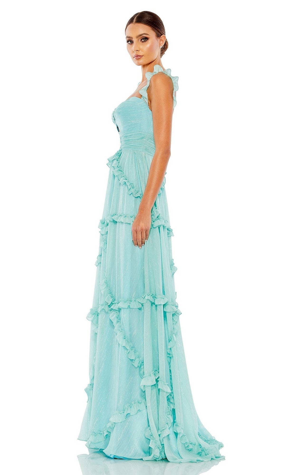 A woman stands diagonally left against a plain white background, wearing the Long Formal Dress 68093 by Mac Duggal— a light blue, ruffle-tiered gown with a fitted bodice and flowing skirt.