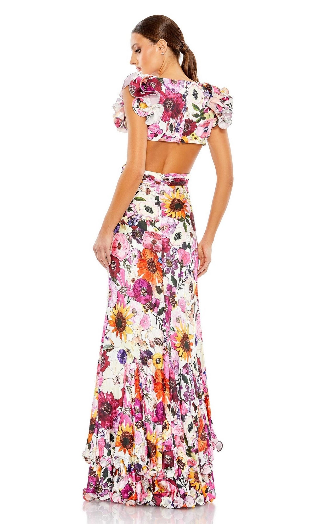 A woman stands facing away, wearing the Mac Duggal 68107 Ruffled Long Print Party Dress, featuring a floral print, ruffled sleeves, an open back, and a fitted silhouette.
