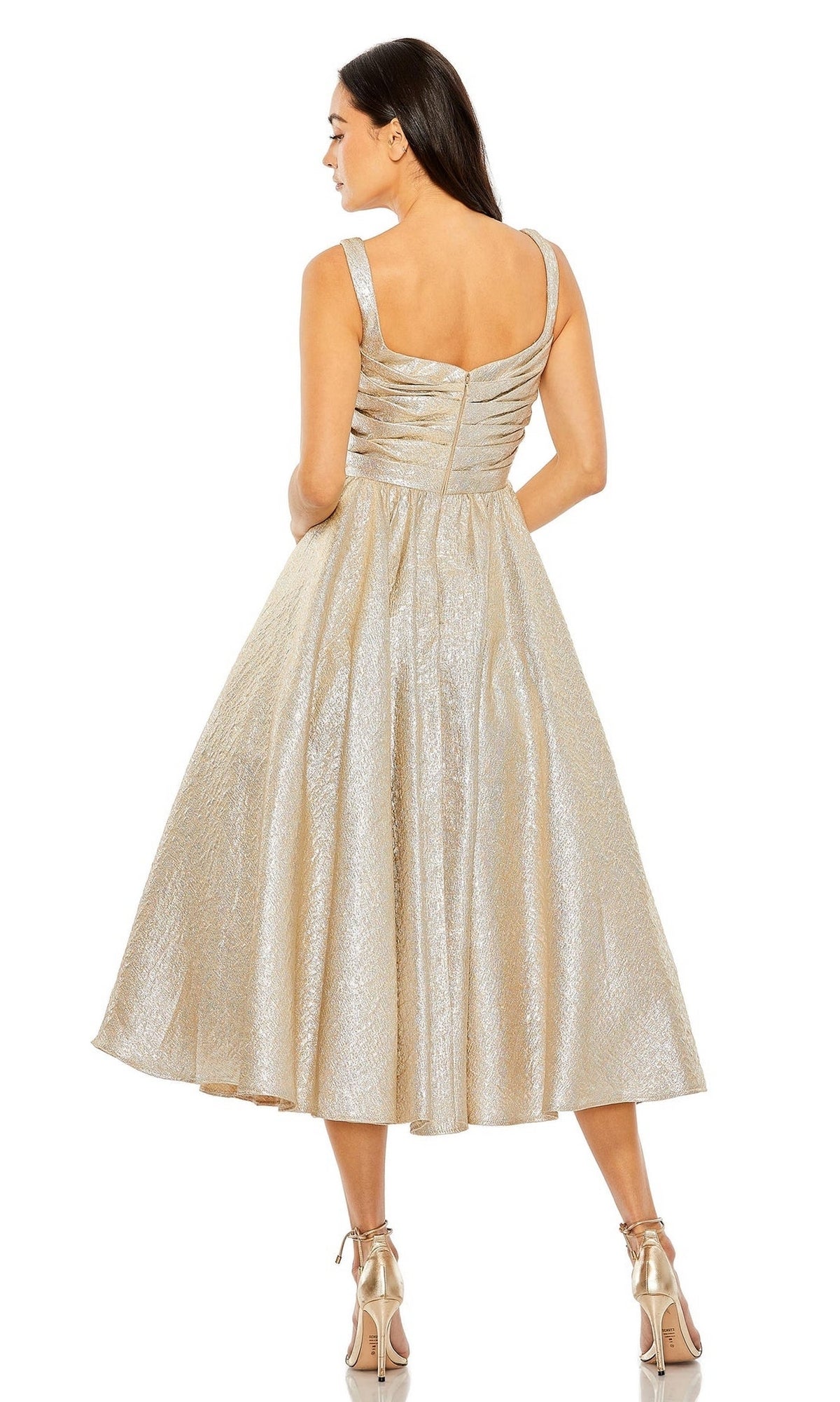 Woman in a sleeveless metallic gold Mac Duggal 68350 tea-length wedding-guest dress with a fitted bodice and flared skirt, seen from the back and wearing gold high heels.