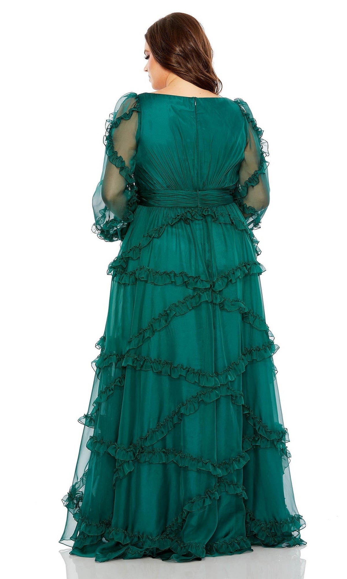 A woman with loose waves faces away, wearing the Long Plus-Size Prom Dress 68425 by Mac Duggal. The formal green gown features a v-neckline, sheer long sleeves, and layered ruffled frills.