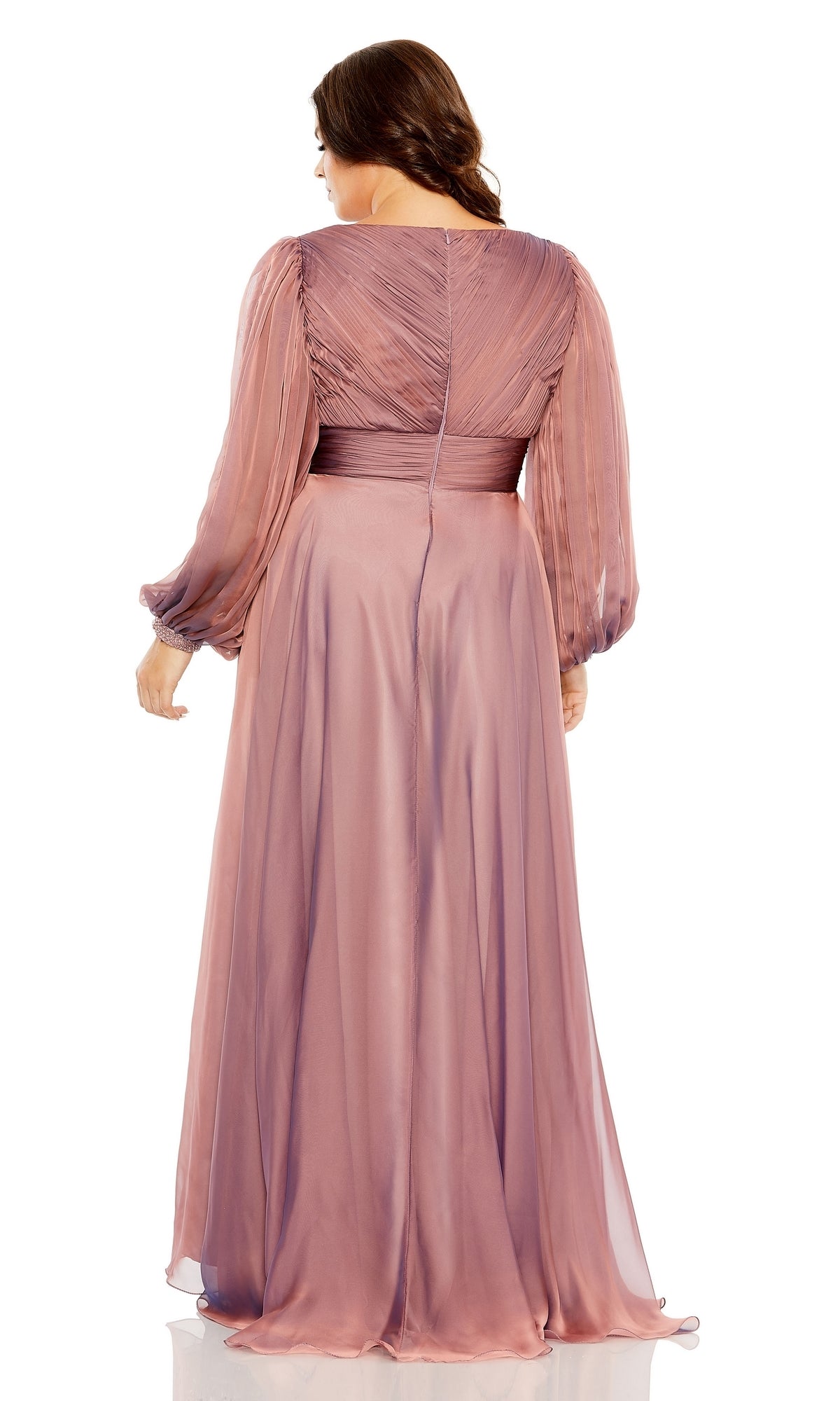 A woman stands facing away, wearing the Long Plus-Size Formal Dress 68431 by Mac Duggal—a mauve, floor-length gown with long sleeves, sheer pleated fabric, and a fitted waistband.